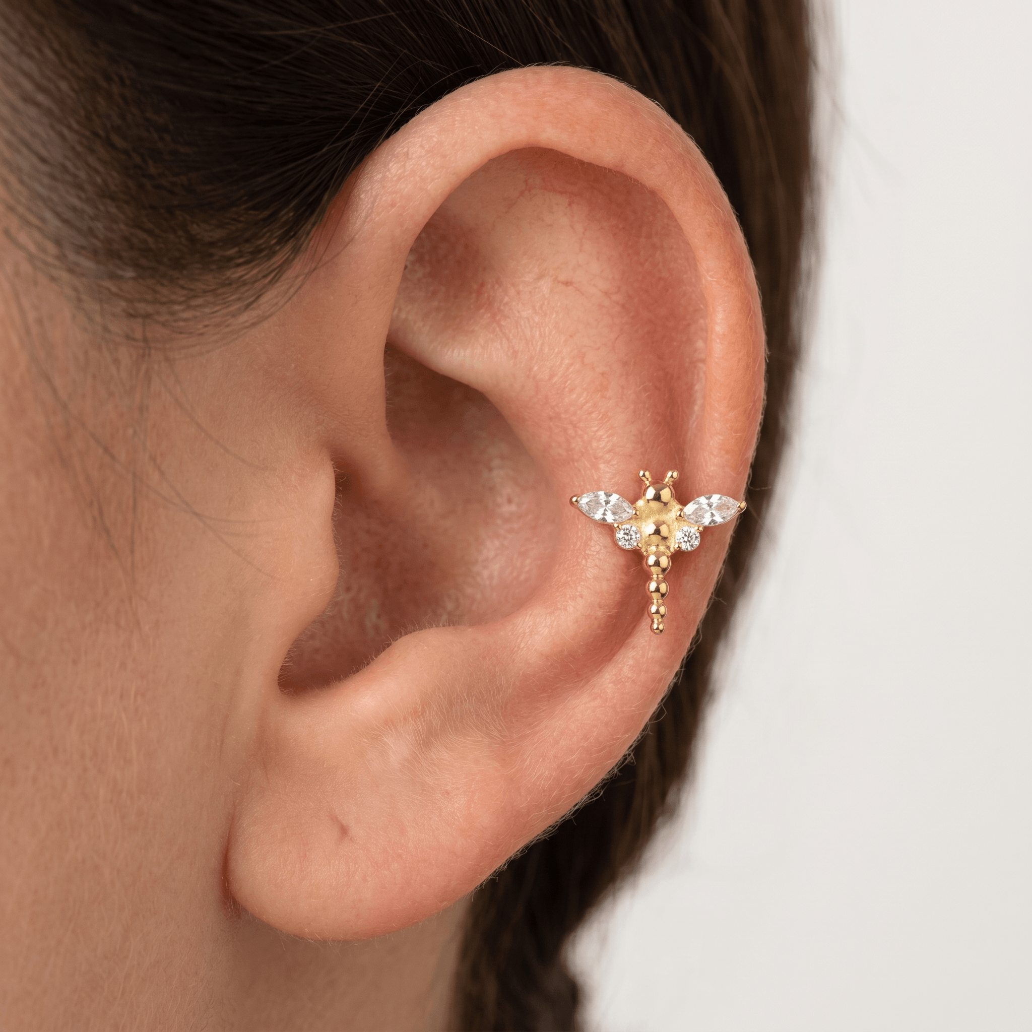 Gold dragonfly stud styled elegantly in a middle cartilage piercing.