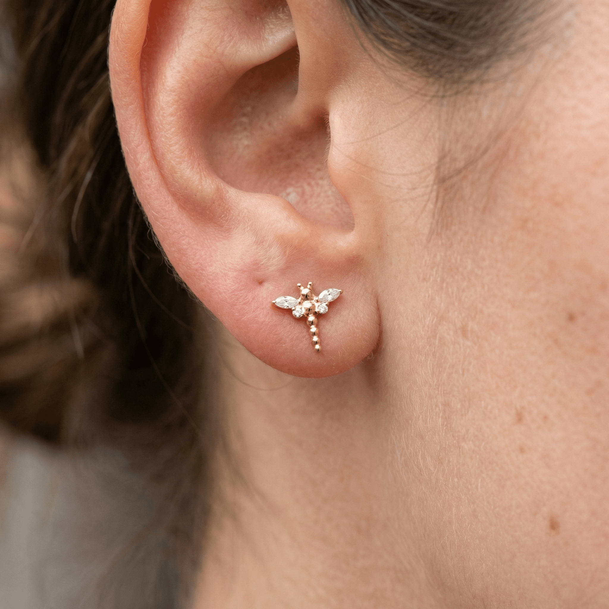 Gold dragonfly ear stud worn in a standard lower piercing.