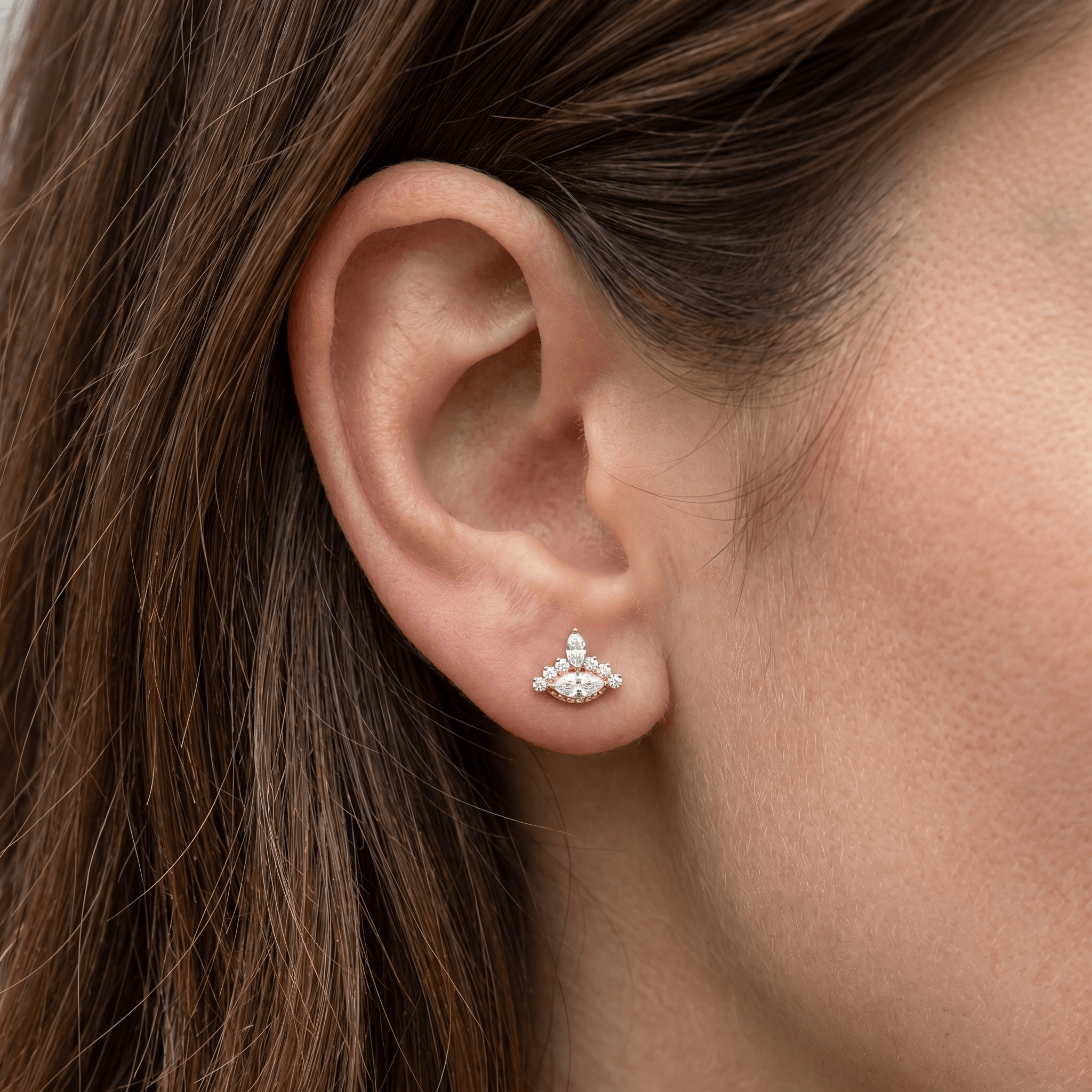 Gold evil eye stud resting perfectly in a standard piercing.