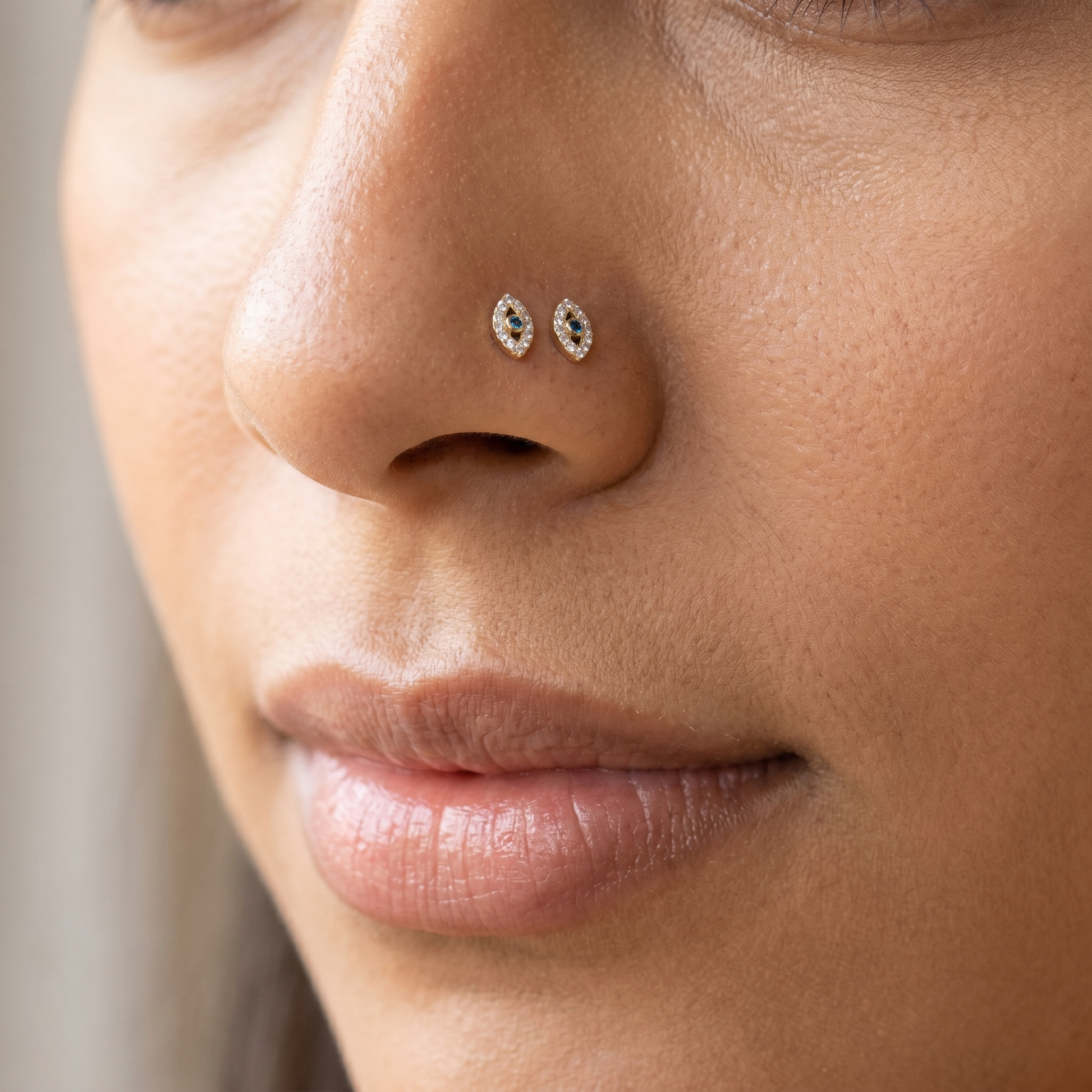 Two evil eye nose studs styled as a double nose piercing on one nostril