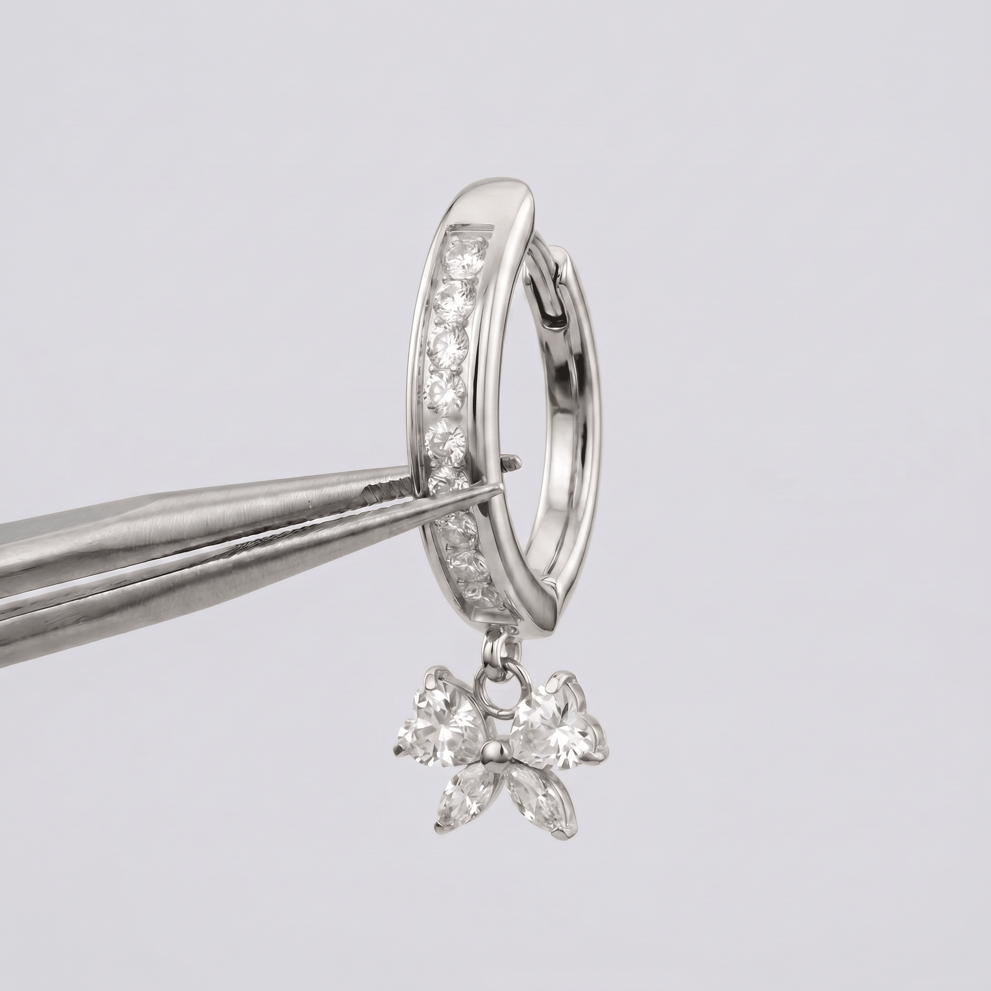 Silver 16g titanium belly jewelry held by metal tweezers.