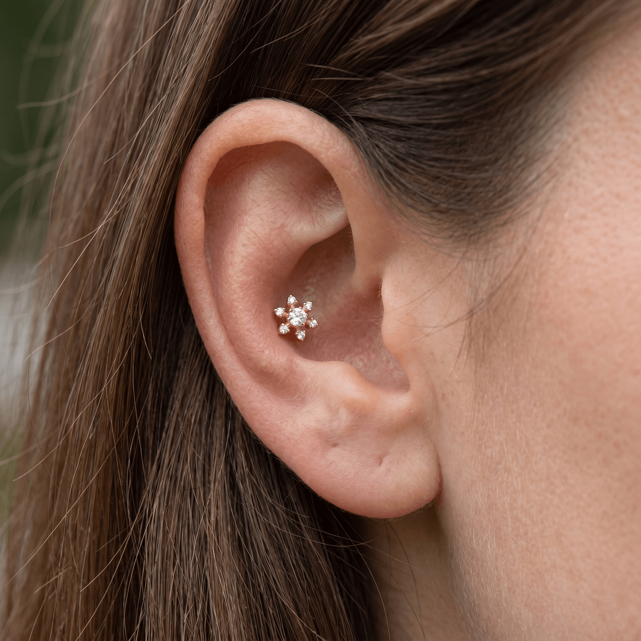 Gold floral cartilage stud styled gracefully in an piercing.