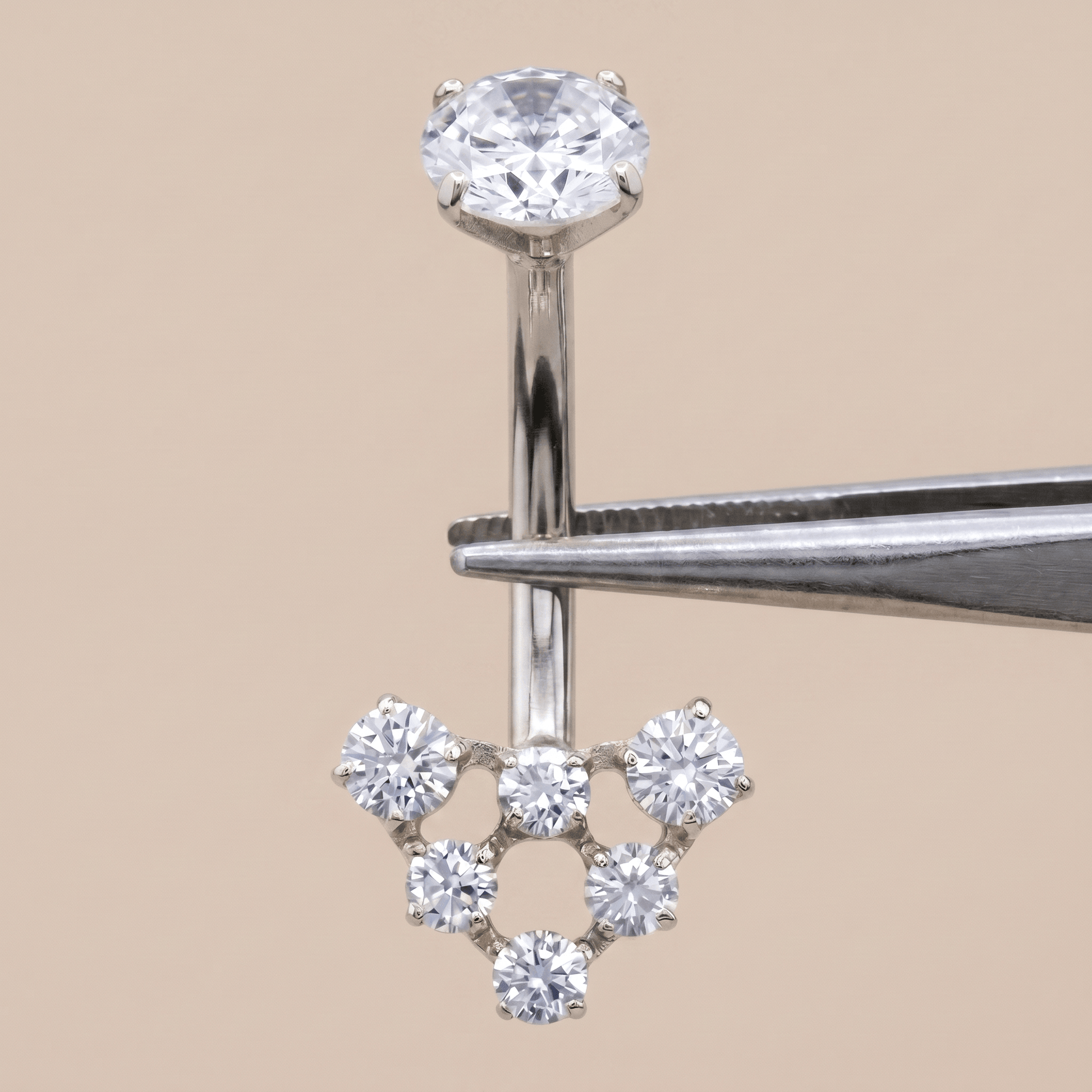 Silver 14g navel ring held securely by metal tweezers.