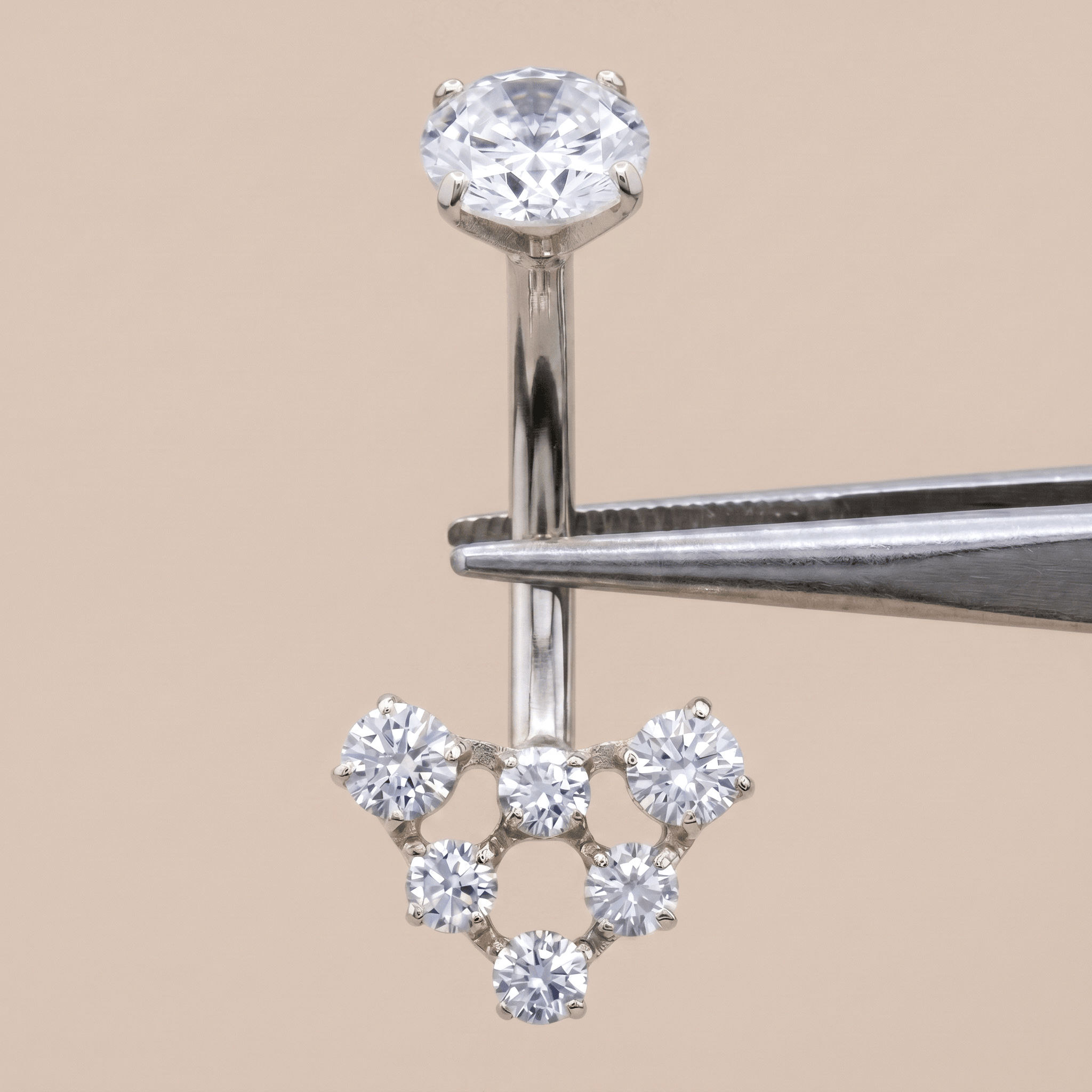 Silver 14g navel ring held securely by metal tweezers.