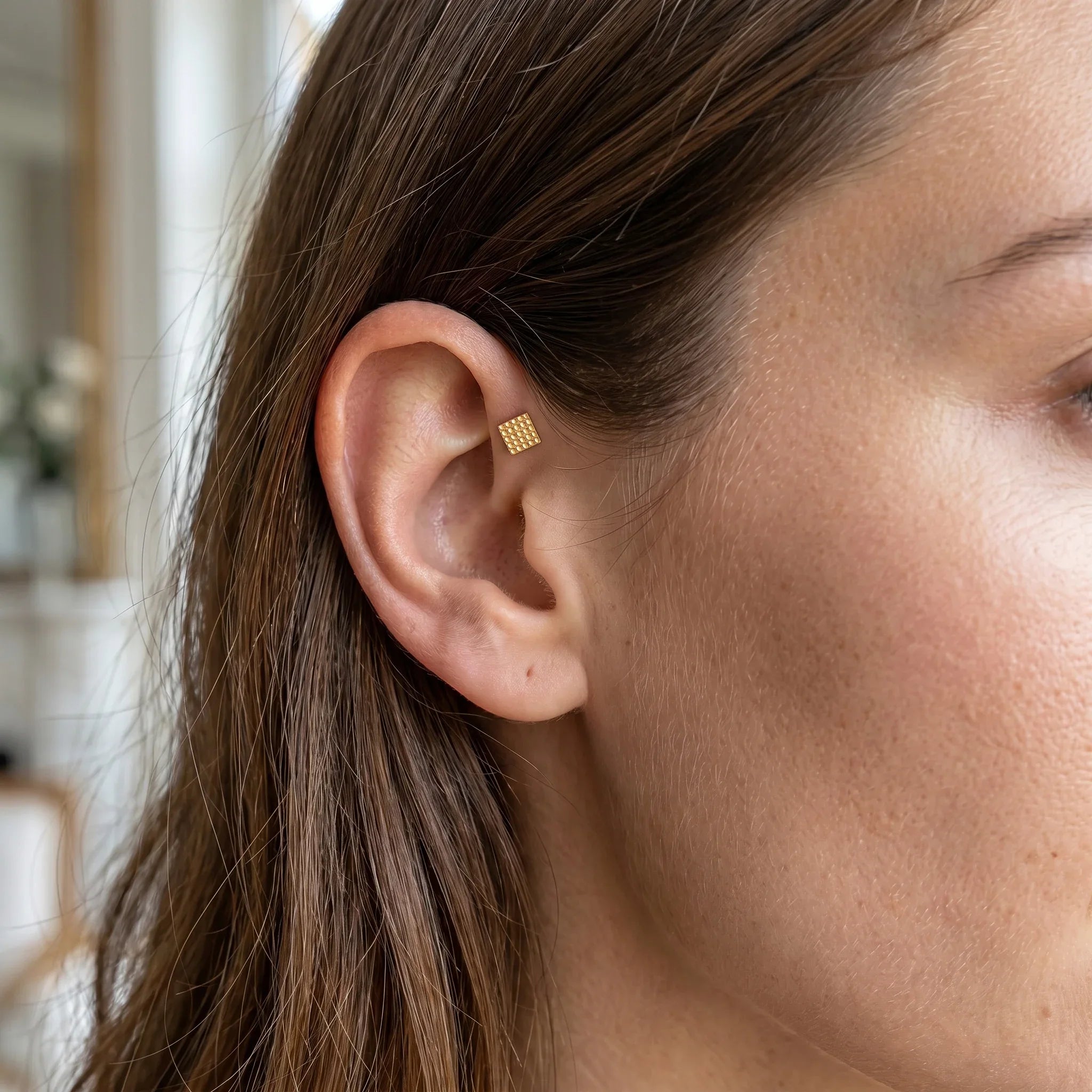 Gold geometric square faux stud worn in a .