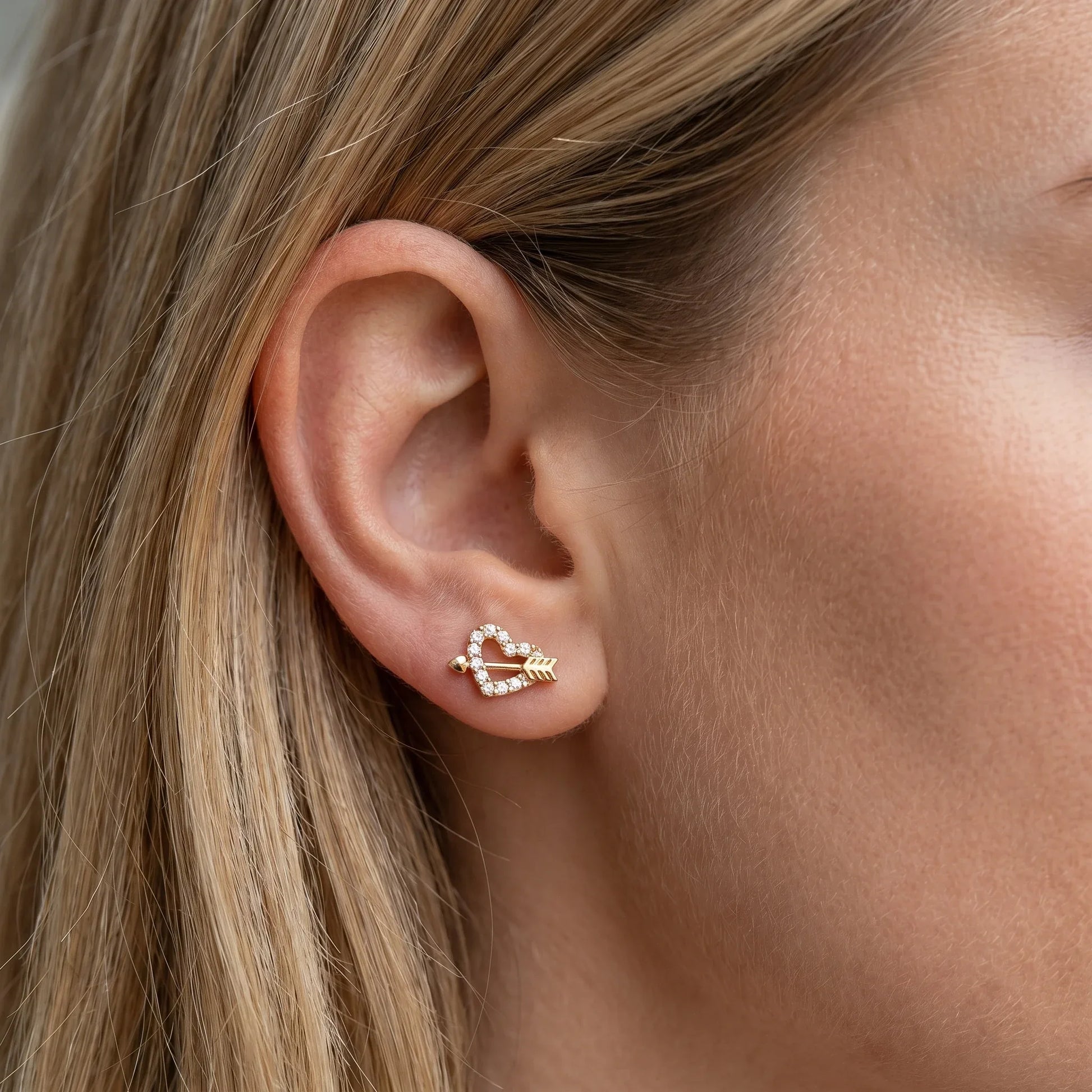 Gold heart arrow stud worn elegantly in a standard placement.