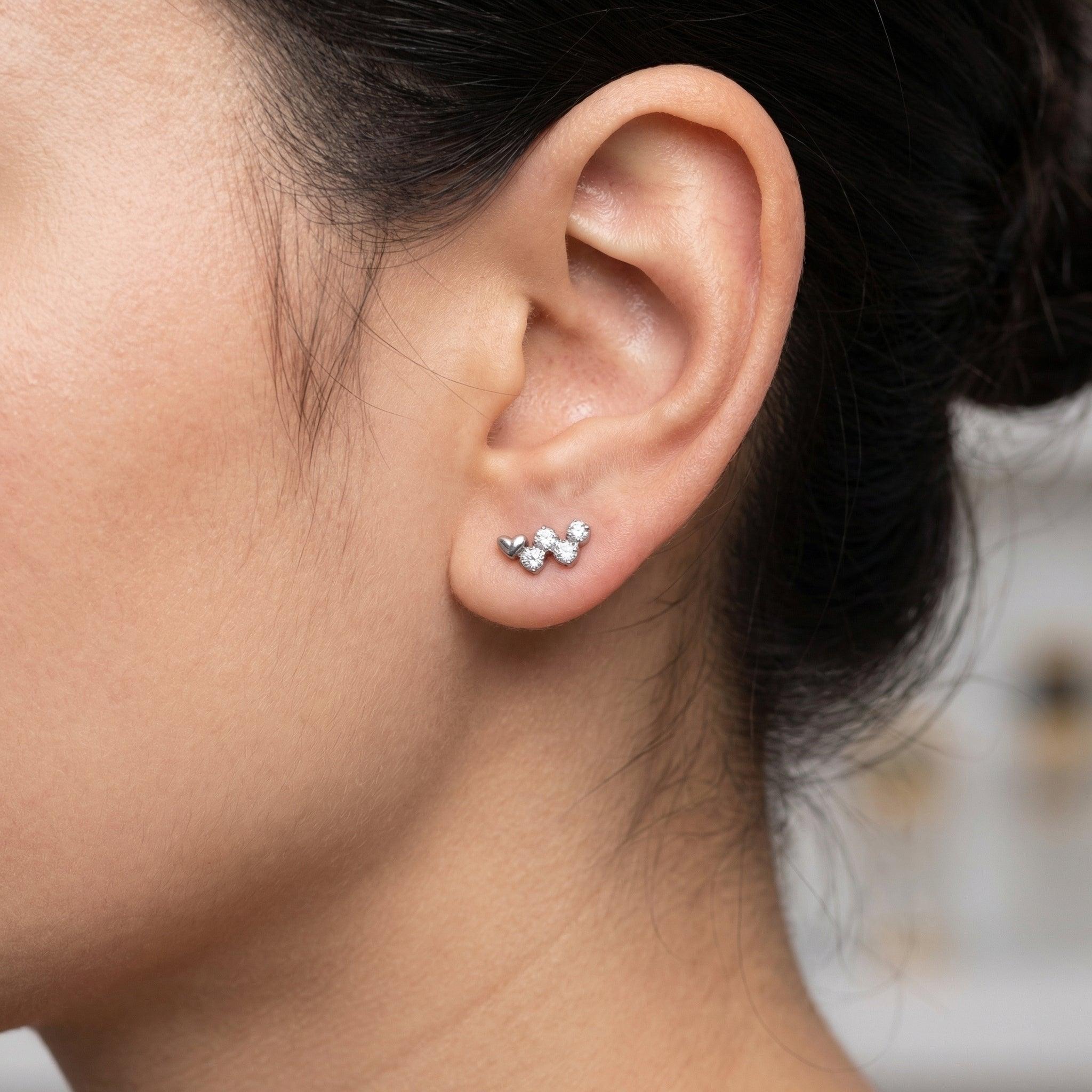 Silver heart four stone cluster ear worn on a lower piercing.