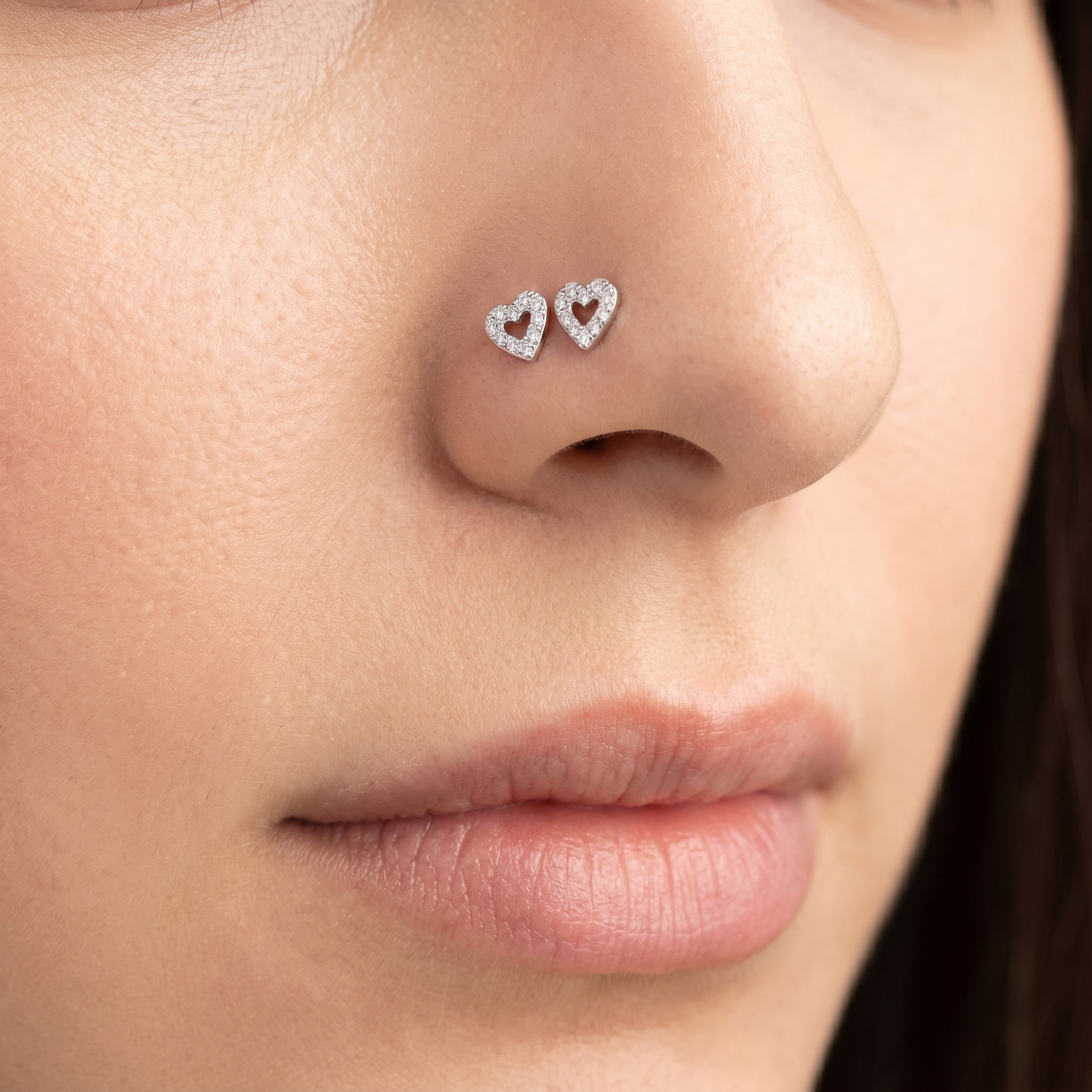 Two heart nose studs styled as a double nose piercing on one nostril