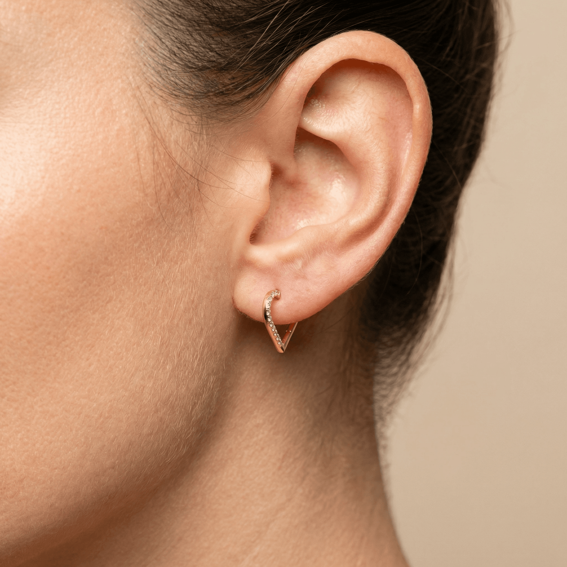 Another side view of a model styling a gold heart shaped hoop