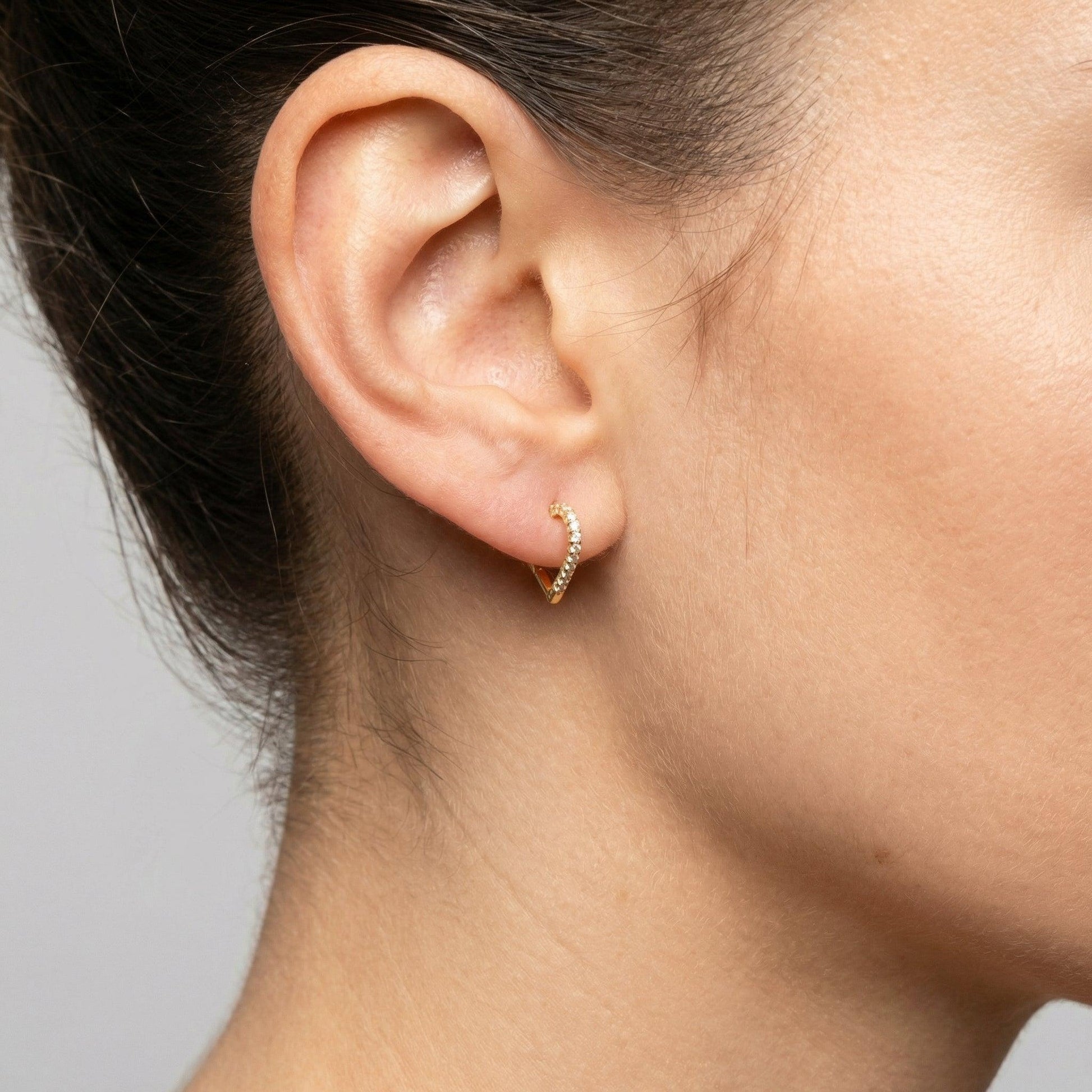 Side view of a gold heart shaped zircon clicker ring worn in