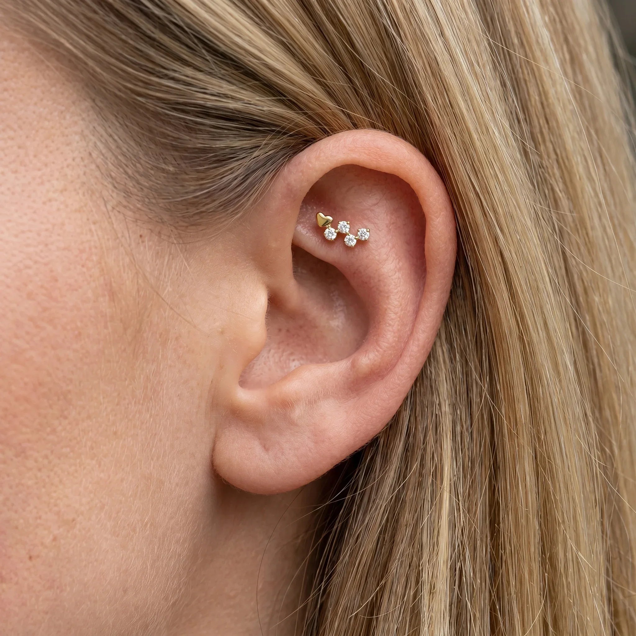 Gold heart cluster faux stud worn beautifully in a female ear.