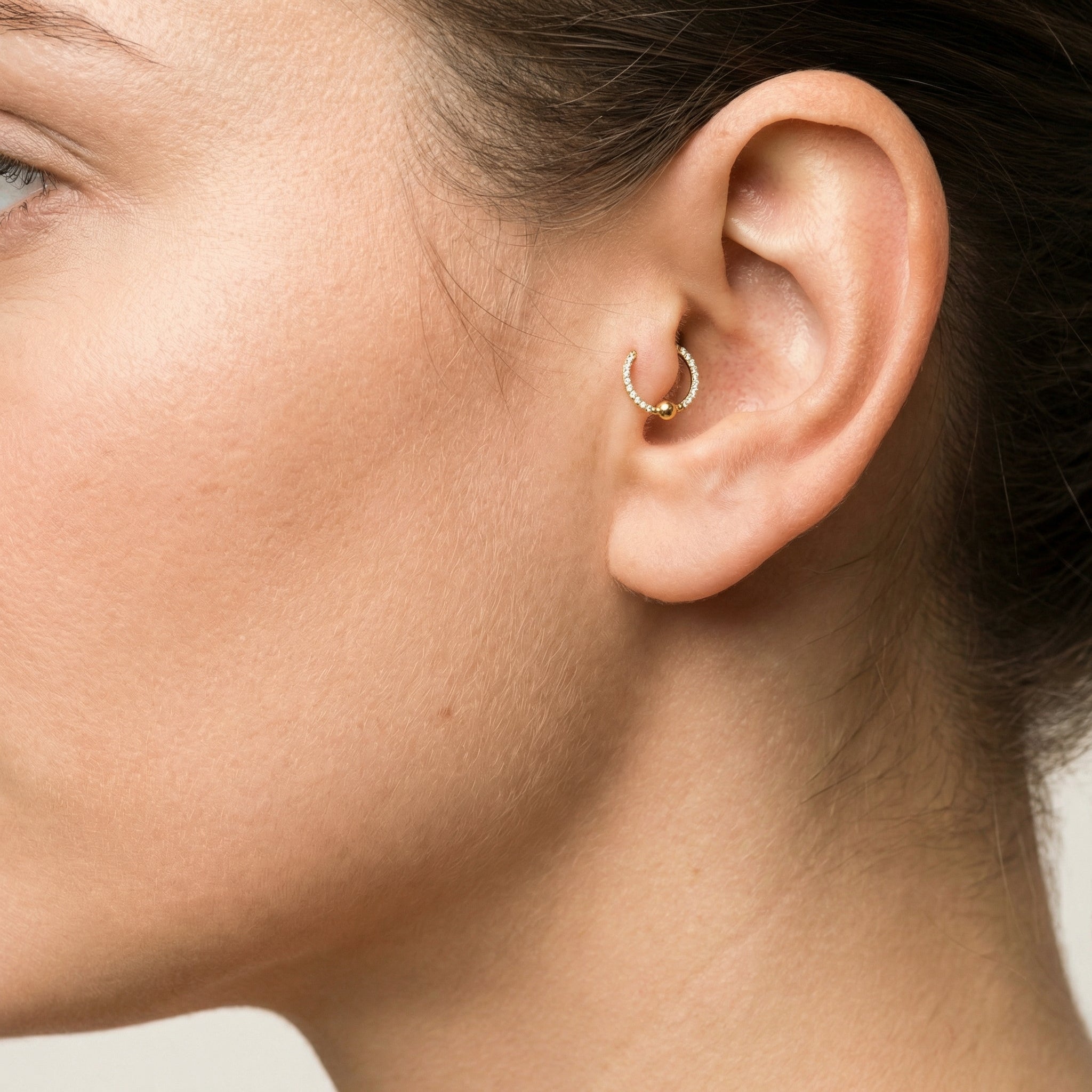 Profile view of a model wearing a gold zircon center bead clicker