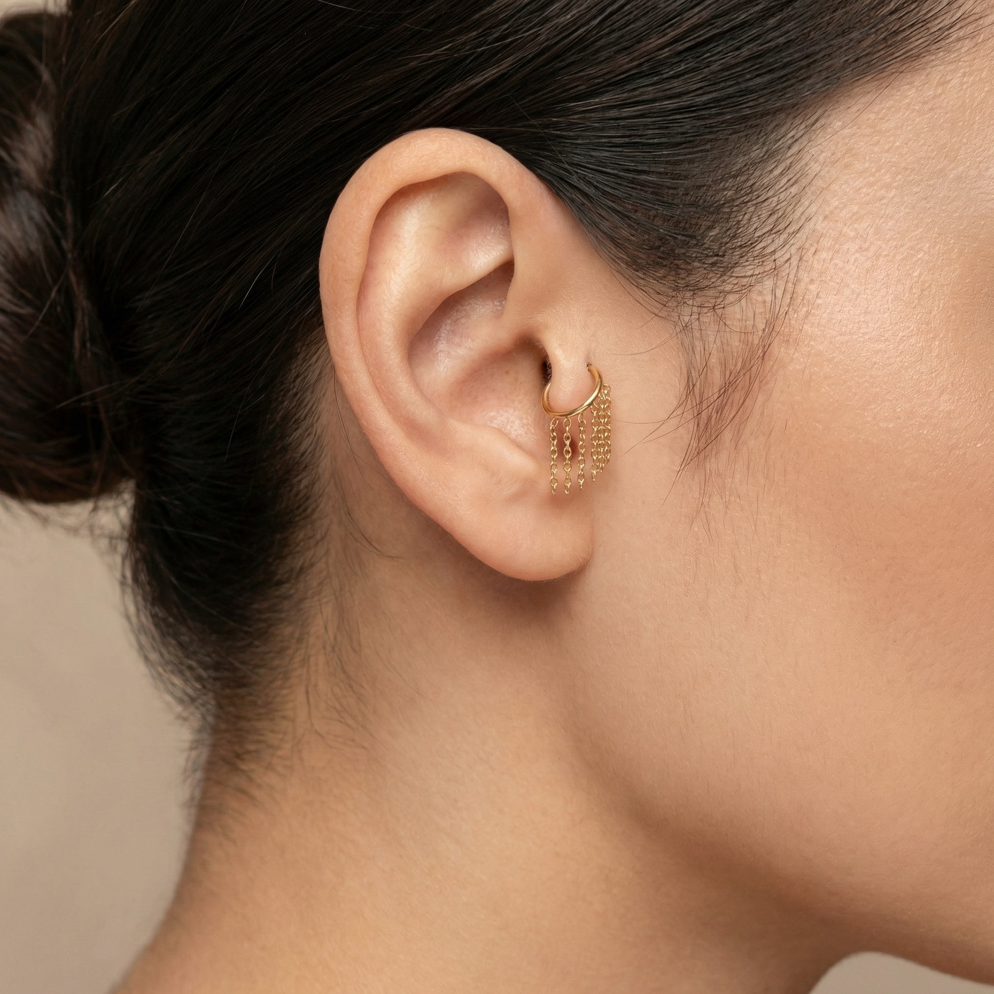 Close-up profile of a gold dangling chain clicker ring resting in an