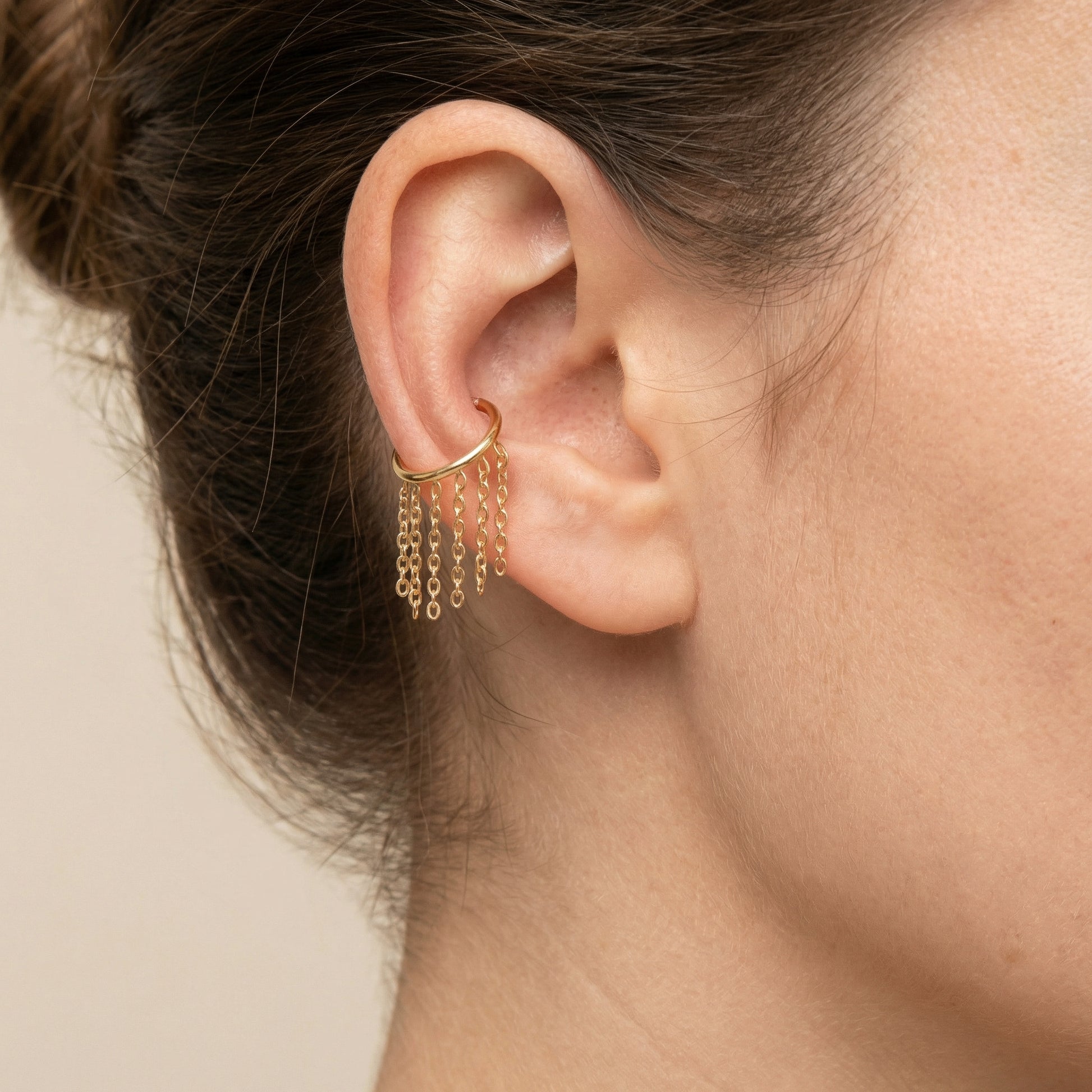 Model showcasing a gold dangling chain clicker cartilage hoop styled neatly within