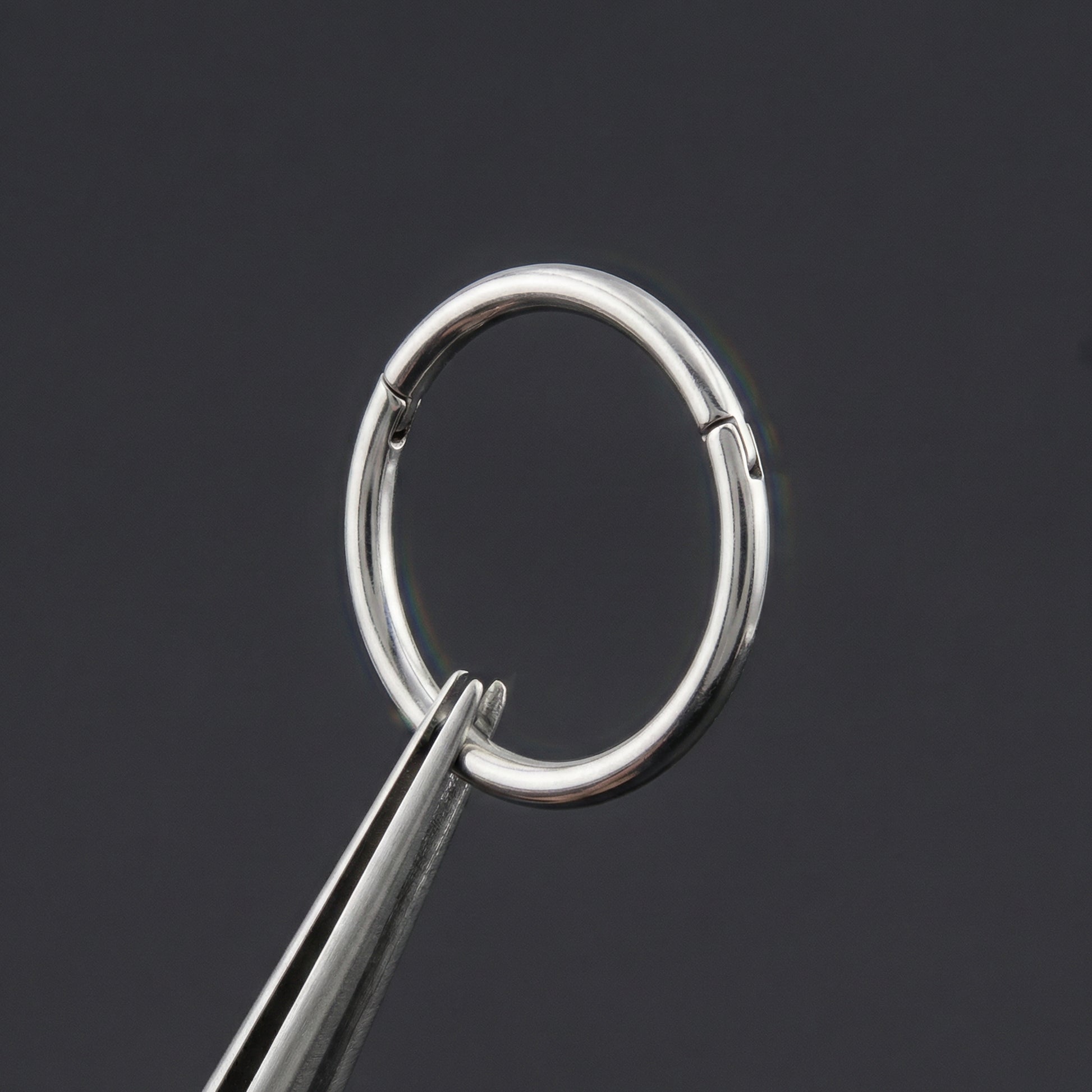 Precision tweezers demonstrating the smooth opening mechanism of a silver titanium hinged