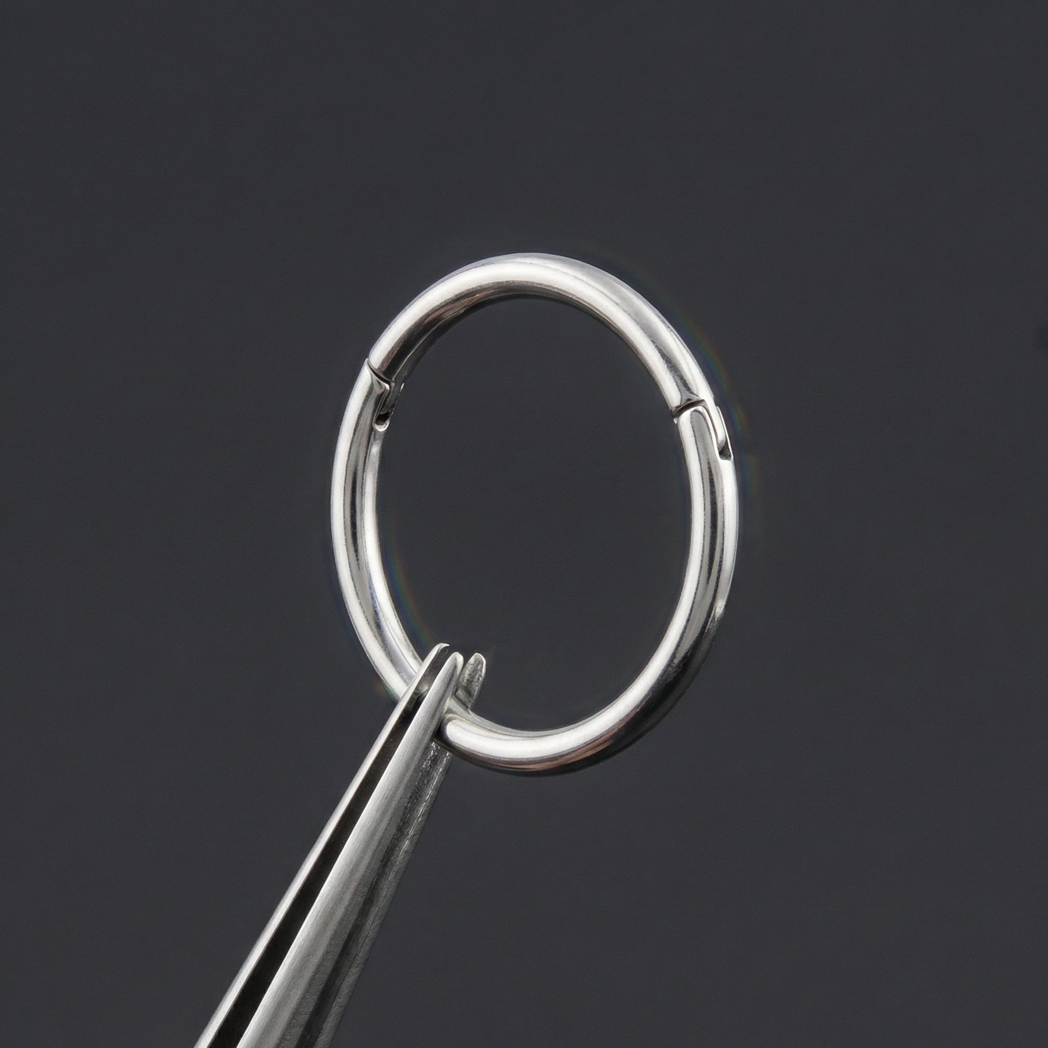 Precision tweezers demonstrating the smooth opening mechanism of a silver titanium hinged