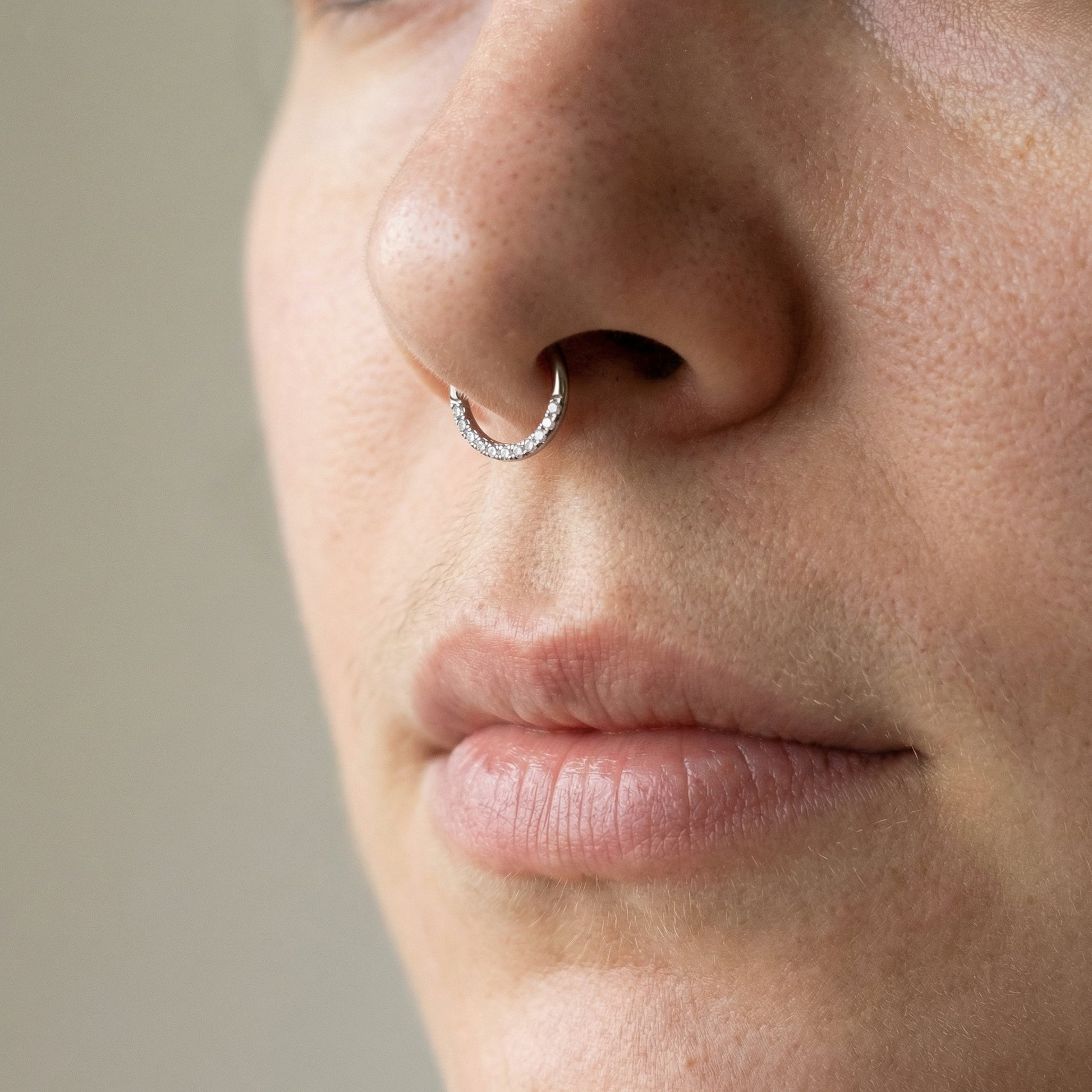 Close-up of a silver zircon hinged clicker hoop styled cleanly inside a