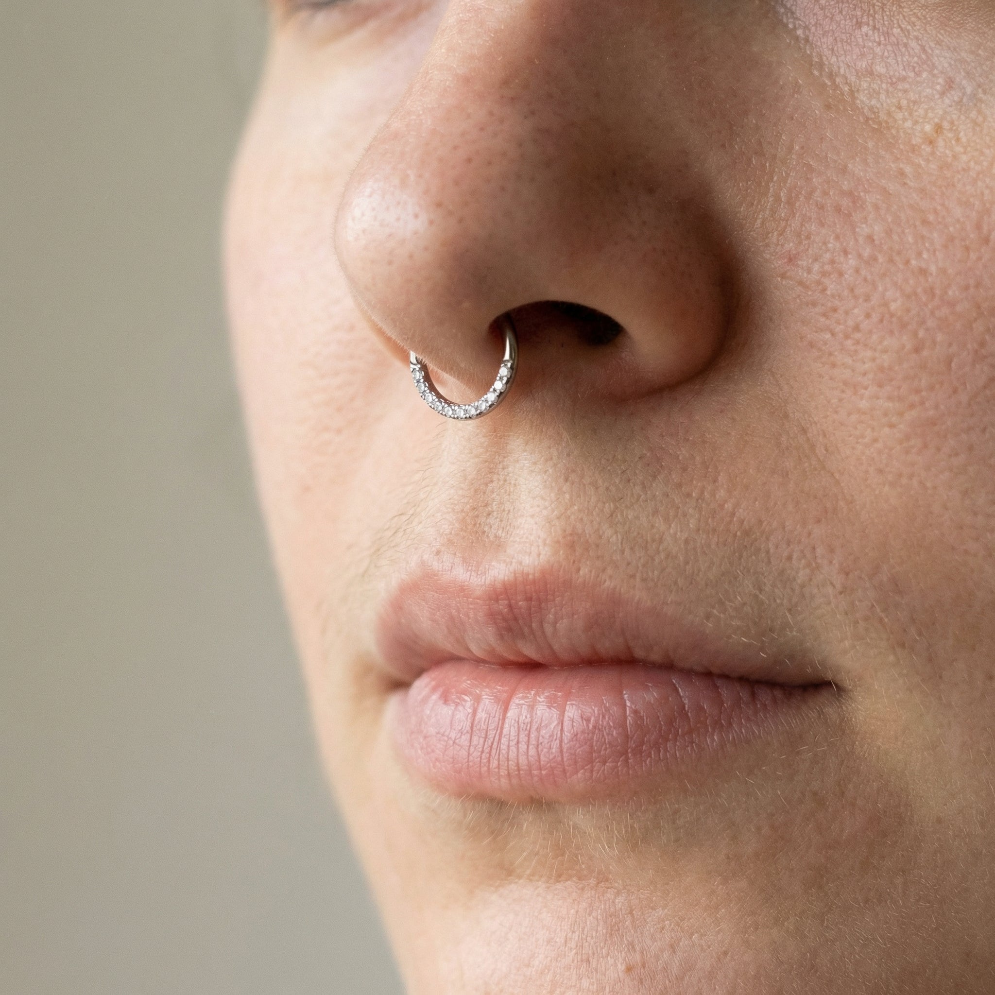 Close-up of a silver zircon hinged clicker hoop styled cleanly inside a
