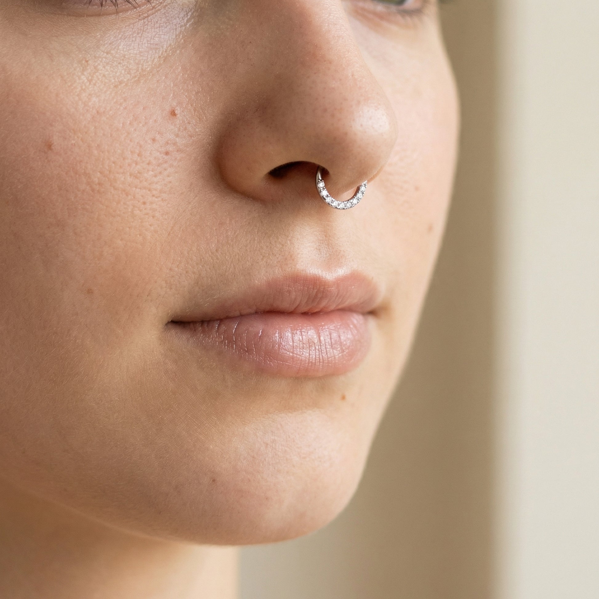 Frontal view of a model wearing a silver zircon clicker hoop in
