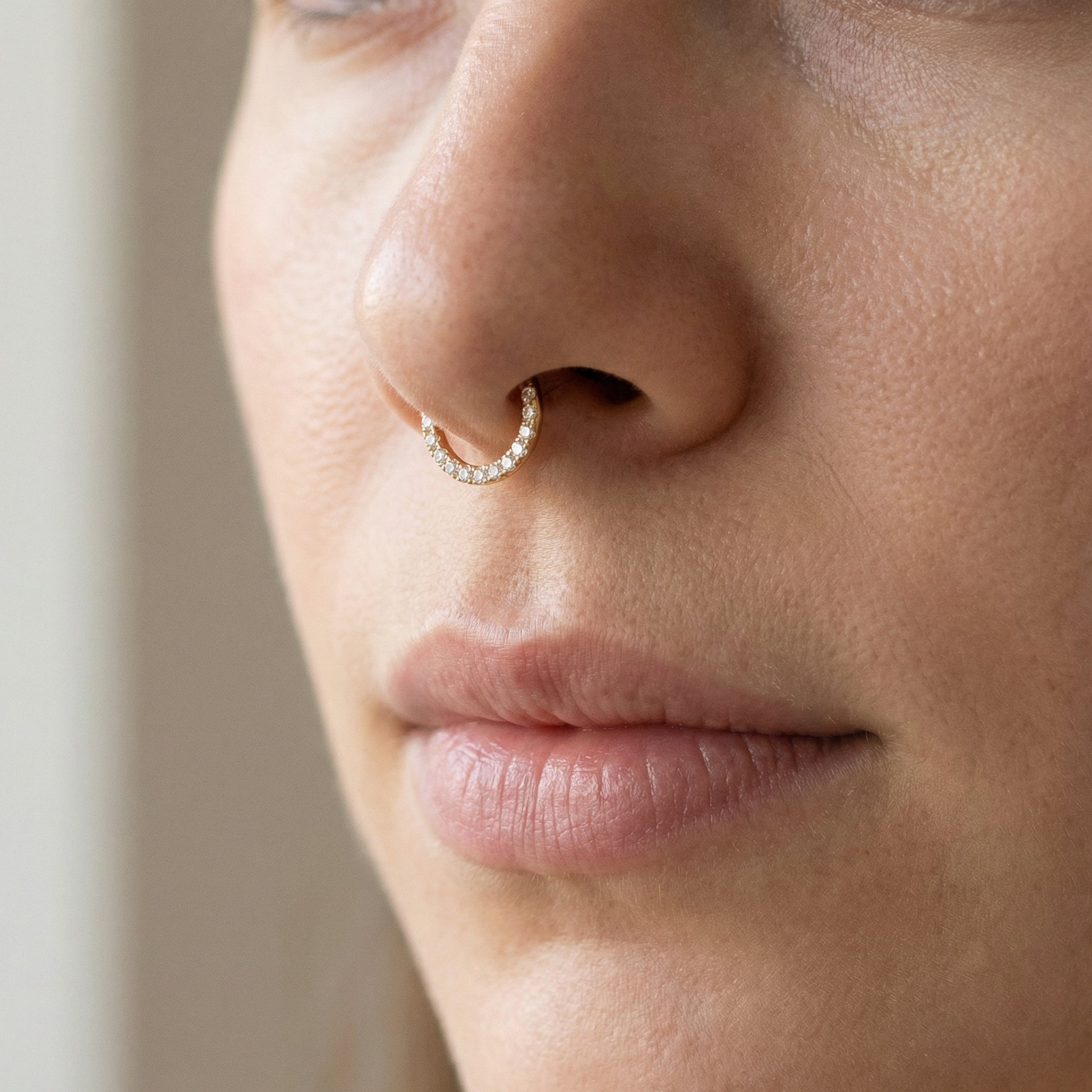 Three-quarter face view of a model showcasing a gold zircon clicker hoop
