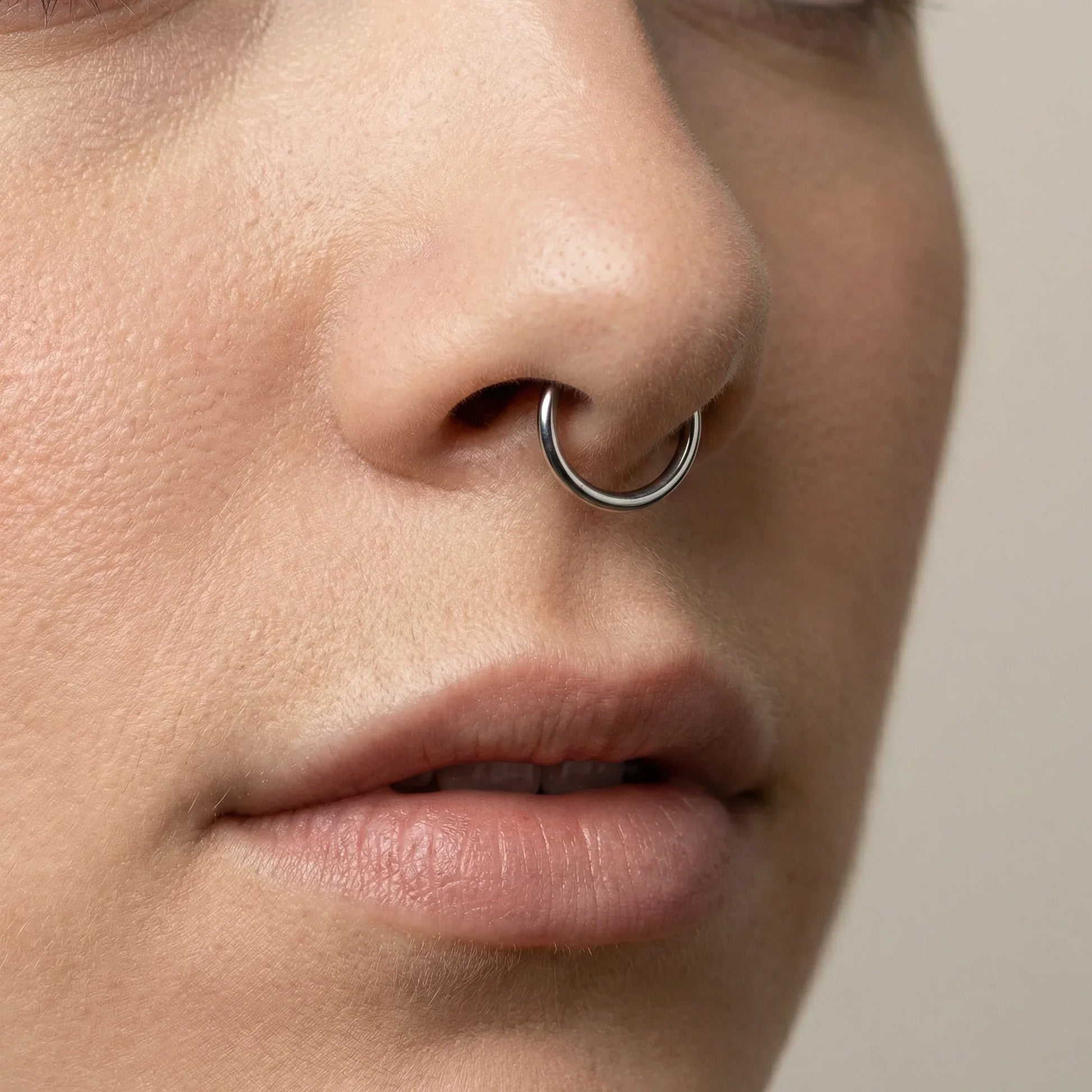 Close-up profile view of a model wearing a gold titanium clicker ring