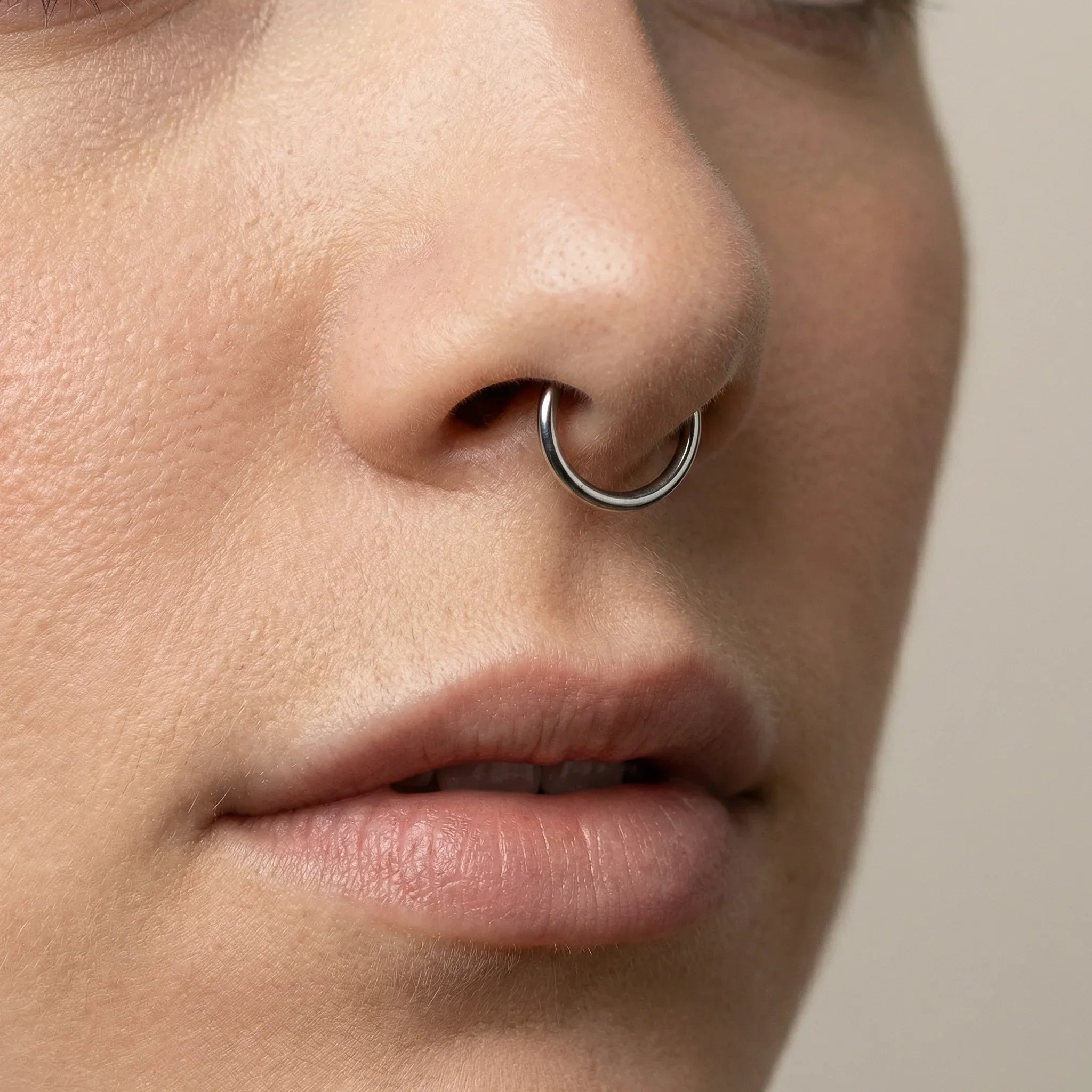 Close-up profile view of a model wearing a gold titanium clicker ring