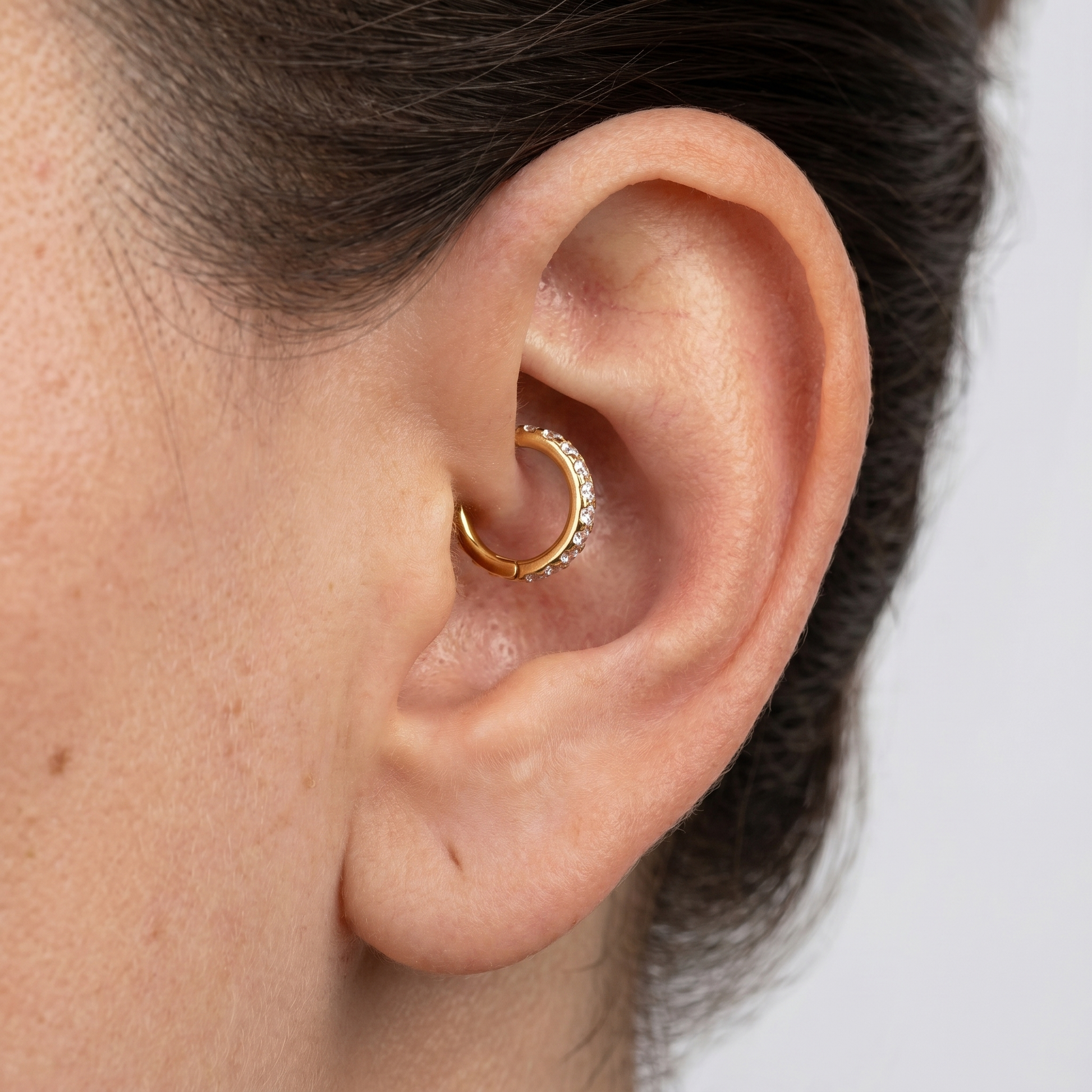 Close-up of a gold zircon clicker worn cleanly in a model's inner