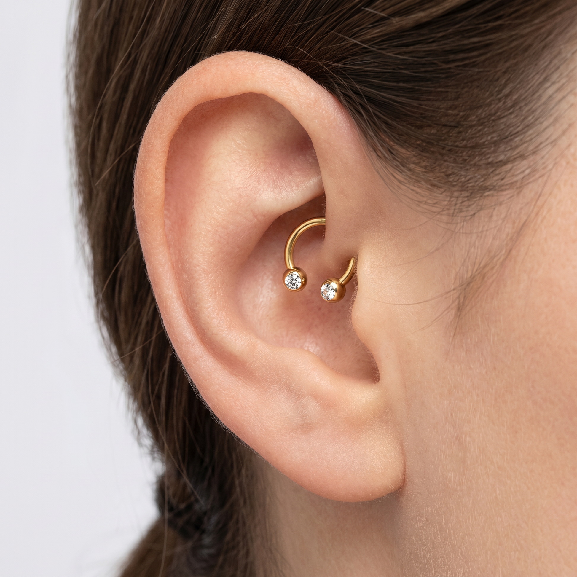 Gold titanium crystal ball horseshoe ring worn elegantly in a female ear.
