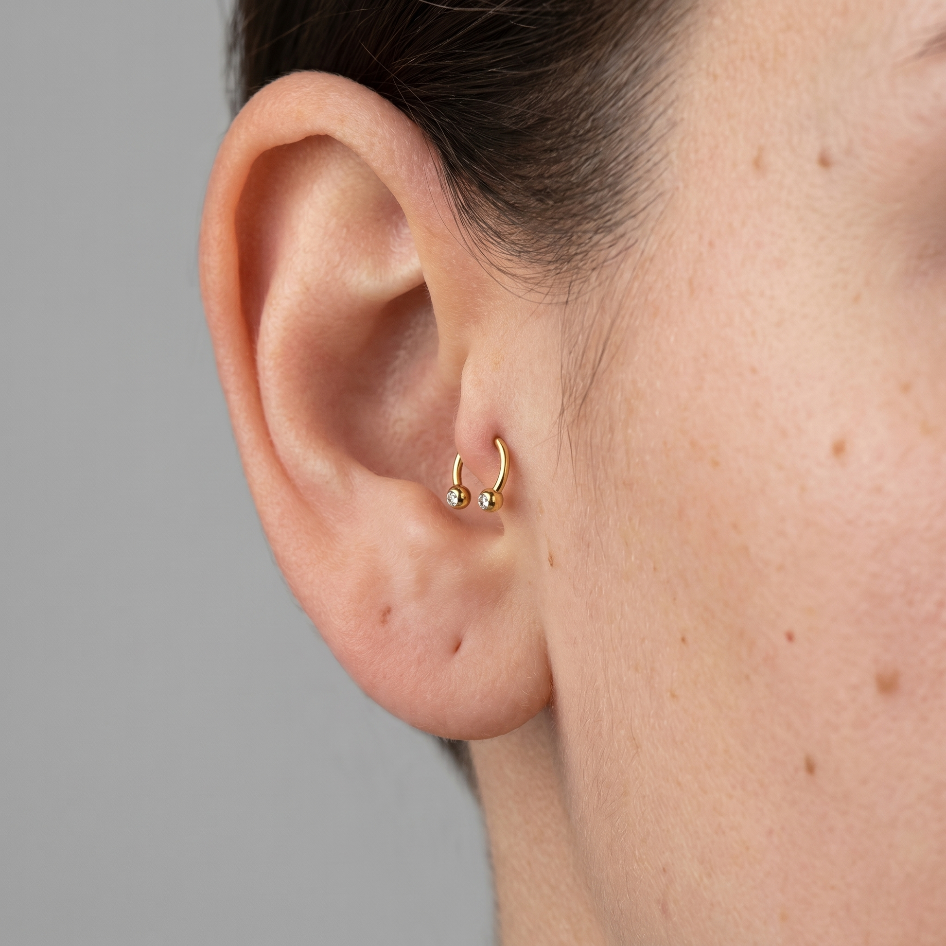 Gold titanium crystal ball horseshoe ring worn in a female piercing.