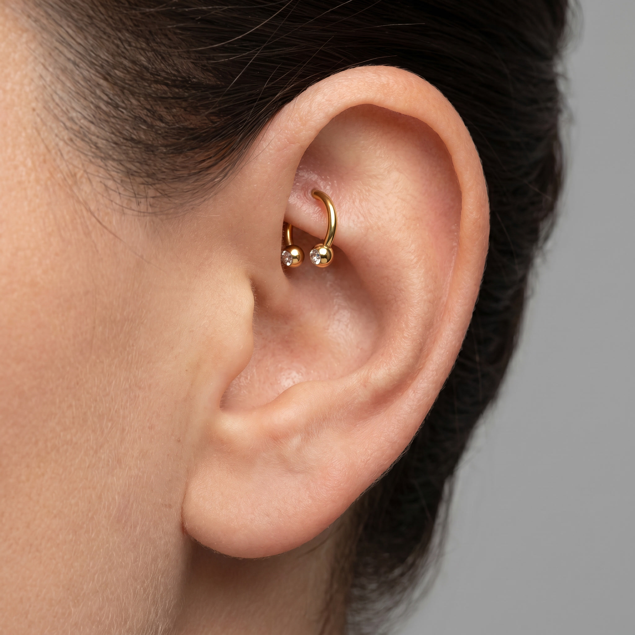 Gold titanium crystal ball horseshoe ring worn in a female piercing.
