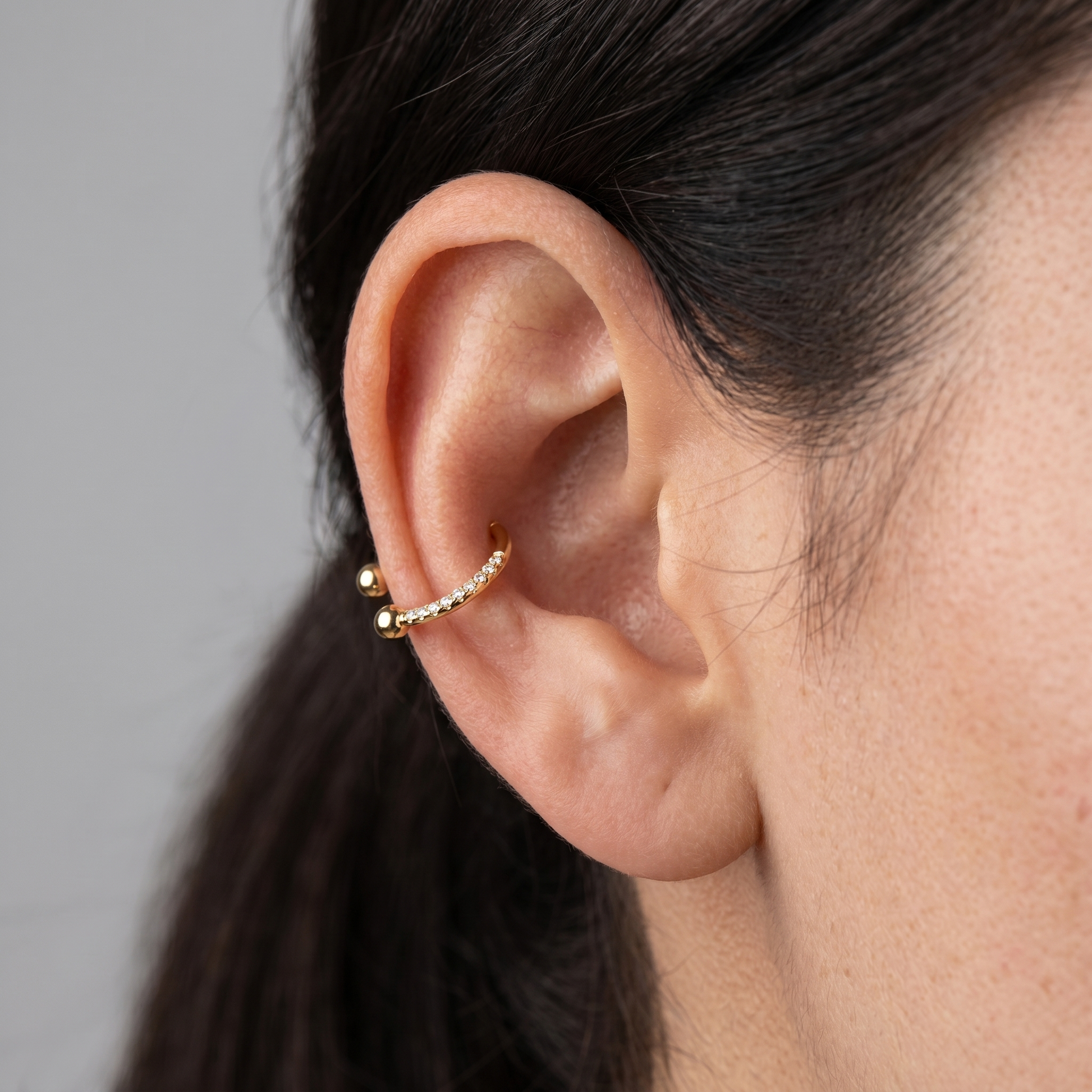 Model showcasing a gold zircon pave hinged horseshoe clicker ring styled securely