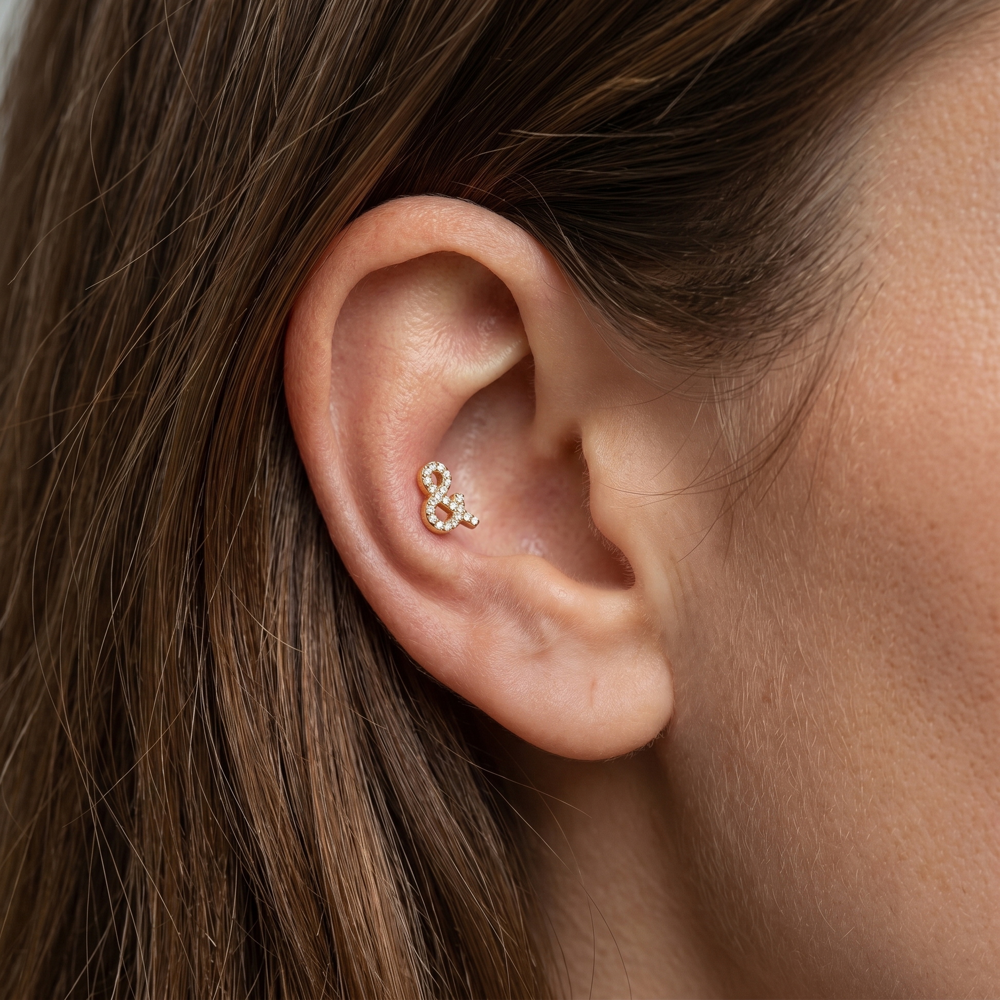 Gold ampersand zircon stud — outer conch piercing placement