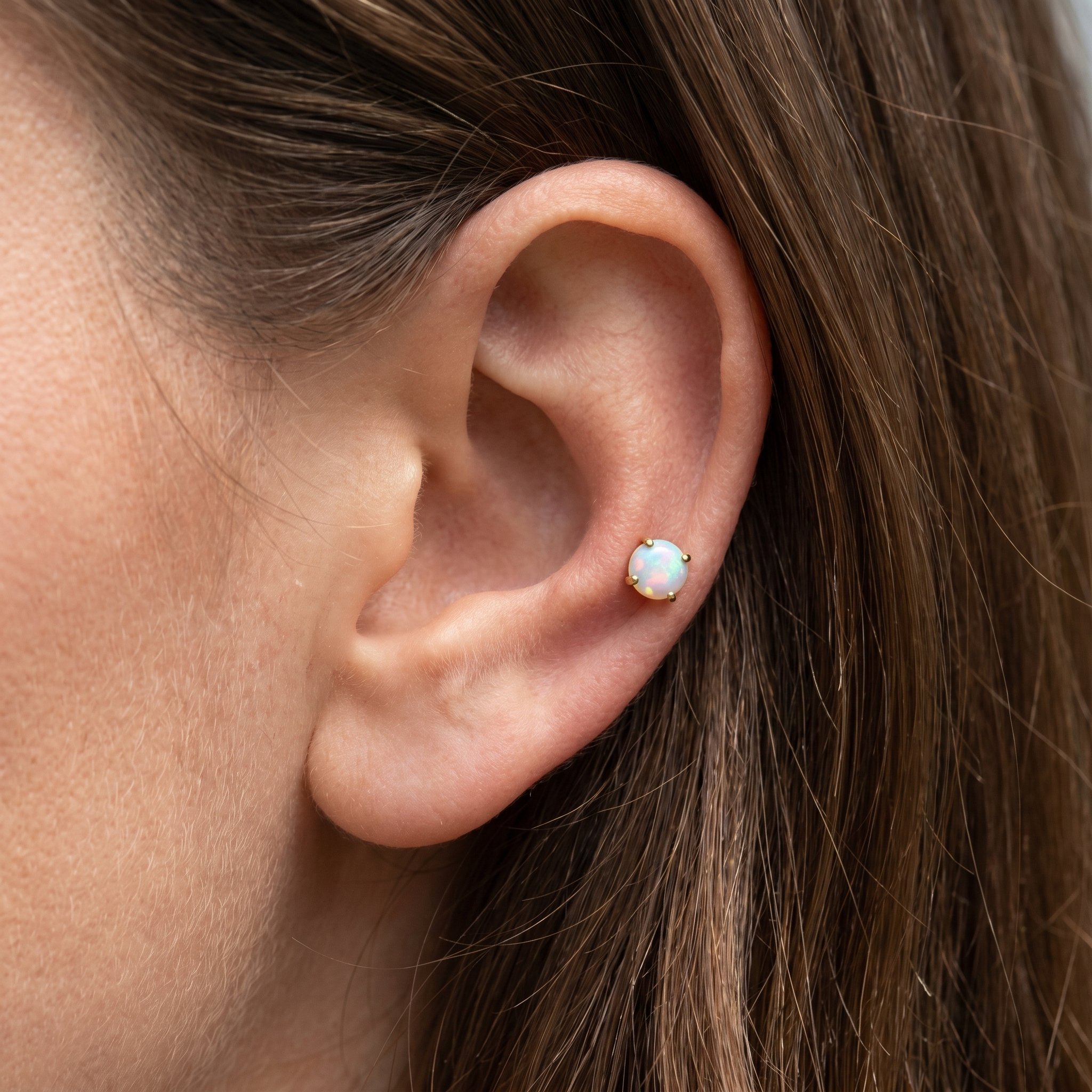 White opal cartilage stud worn in a piercing.