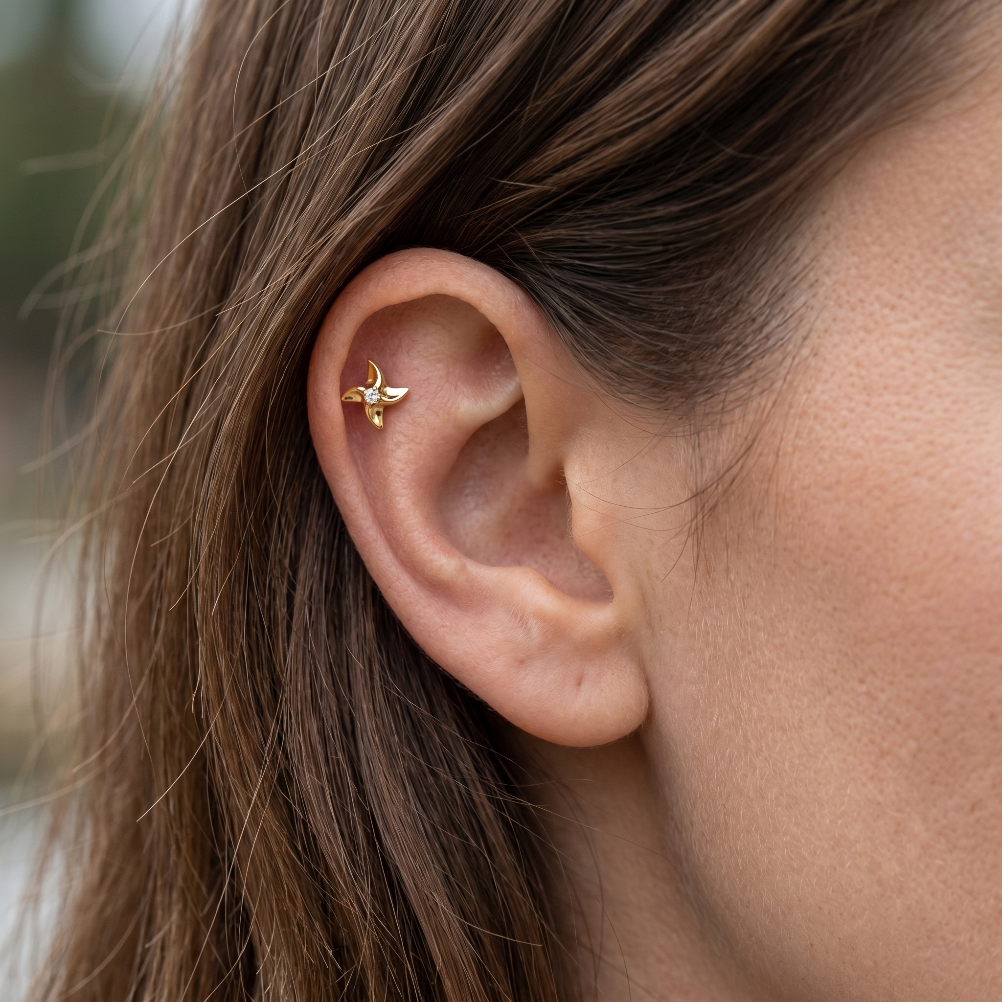 Gold pinwheel piercing stud worn beautifully in a female ear.