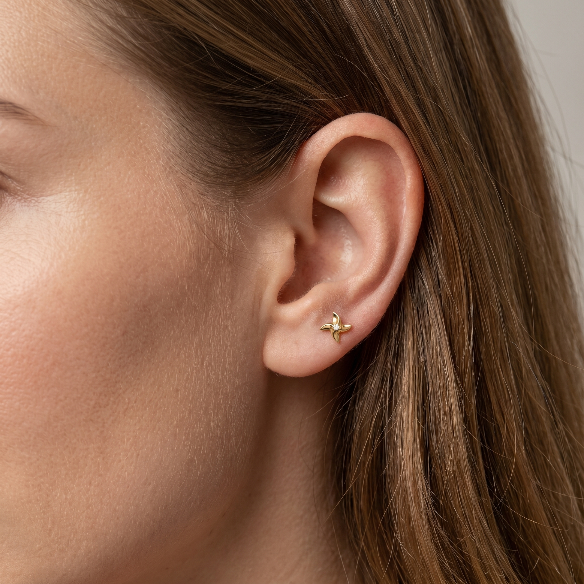 Gold pinwheel zircon medusa stud — anti tragus placement