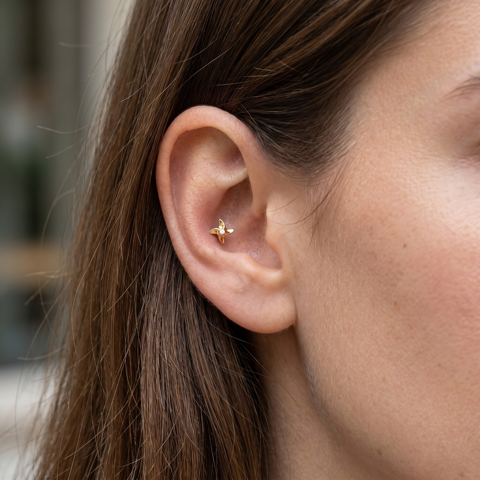 Gold pinwheel piercing stud styled in an piercing.