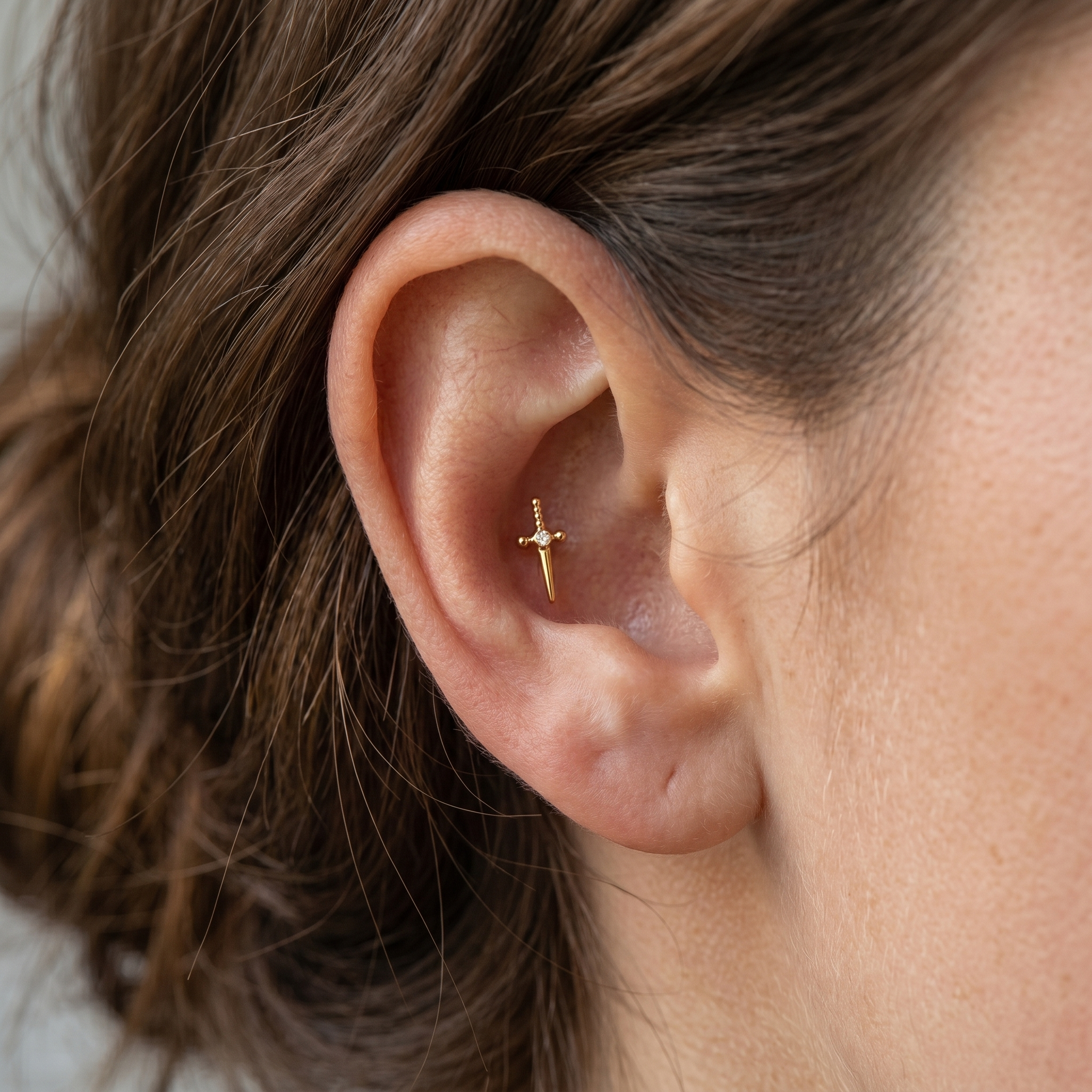 Gold dagger zircon stud — conch ear placement