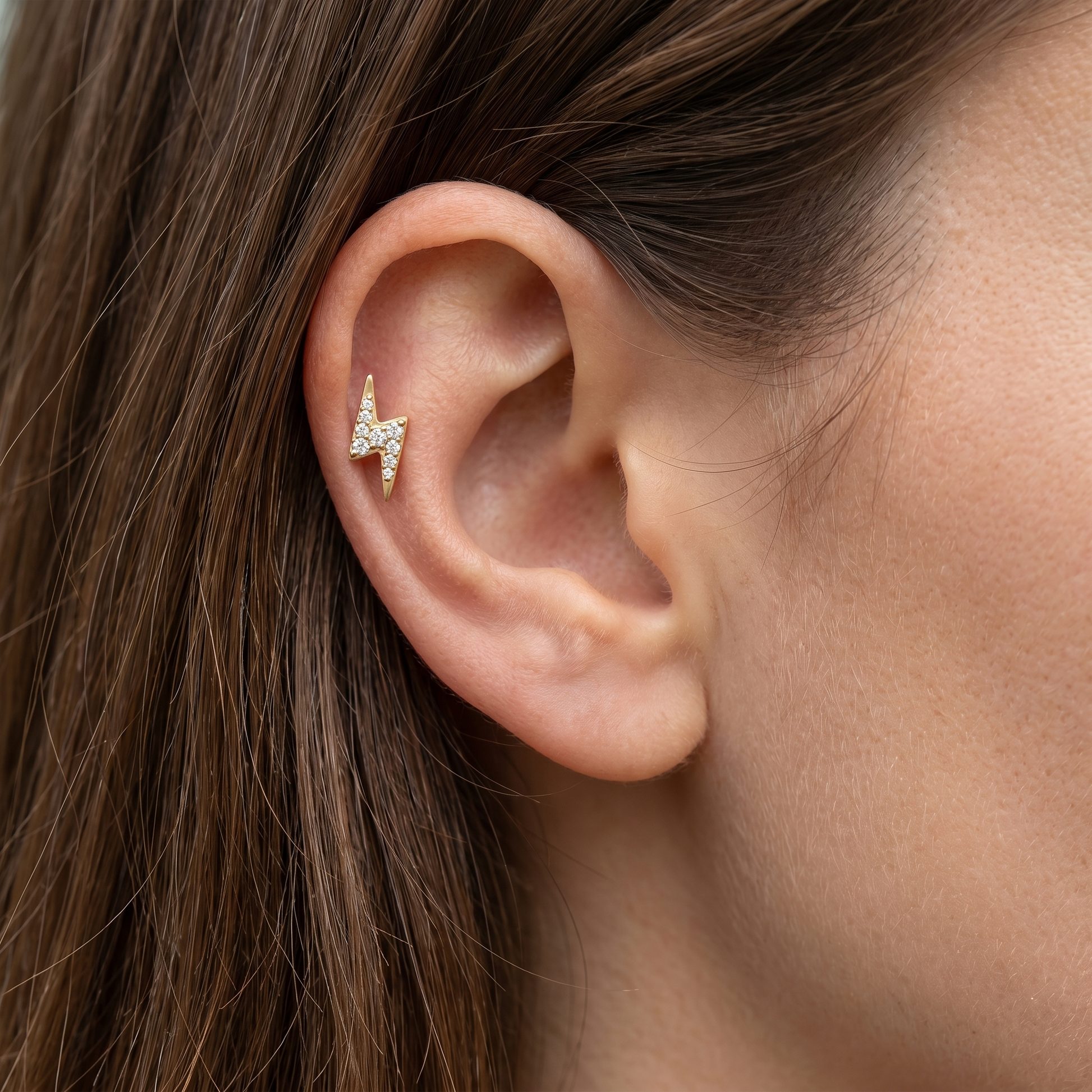 Gold lightning bolt piercing jewelry in a 16G ear cartilage stack.