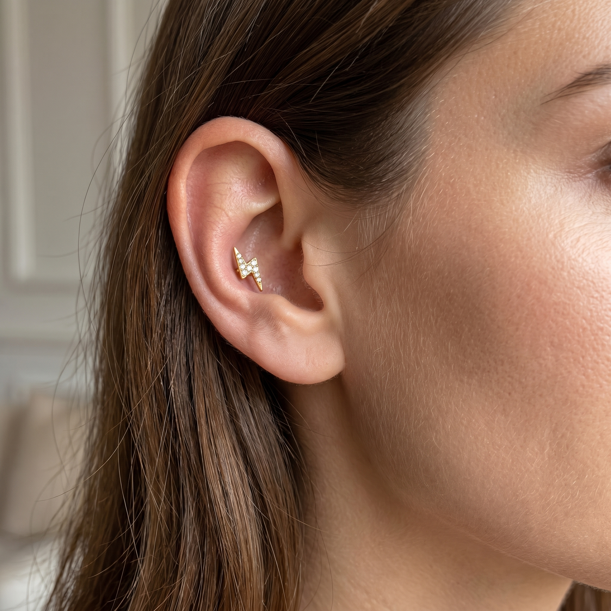 Gold lightning bolt piercing jewelry in a 16G ear cartilage stack.