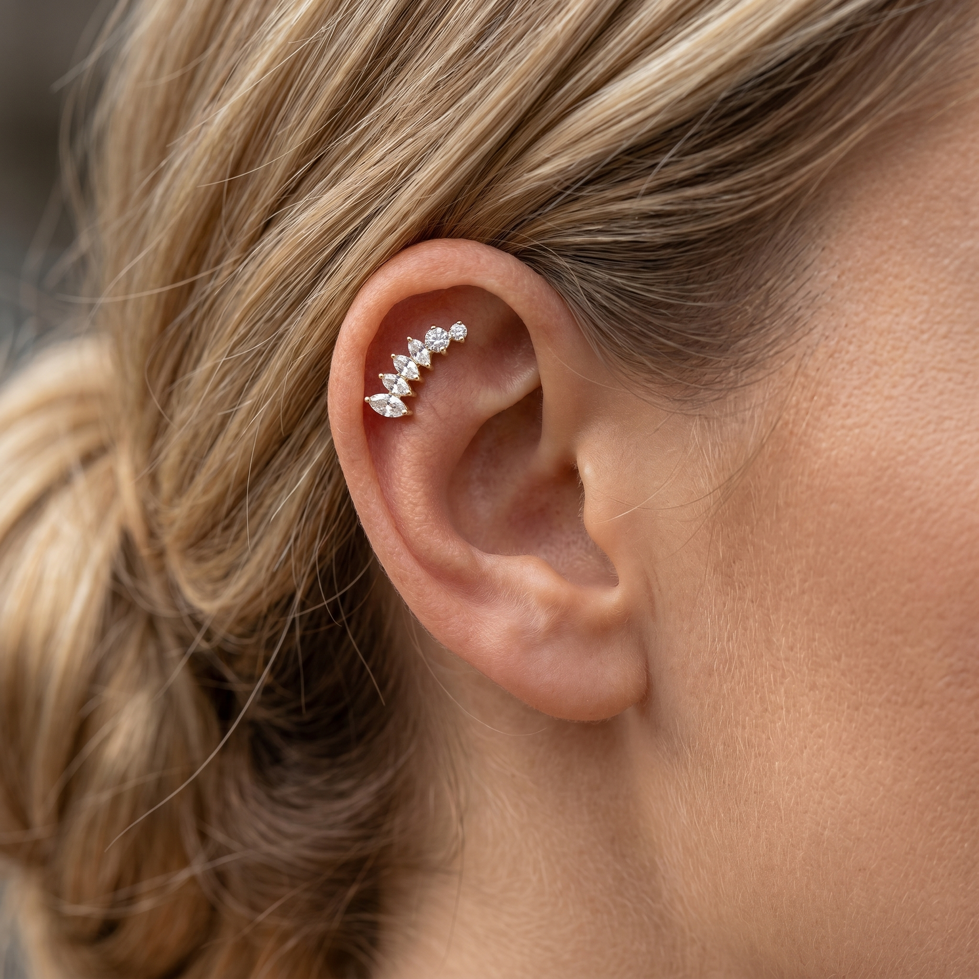 Side view profile close-up of a model wearing a gold curved marquise