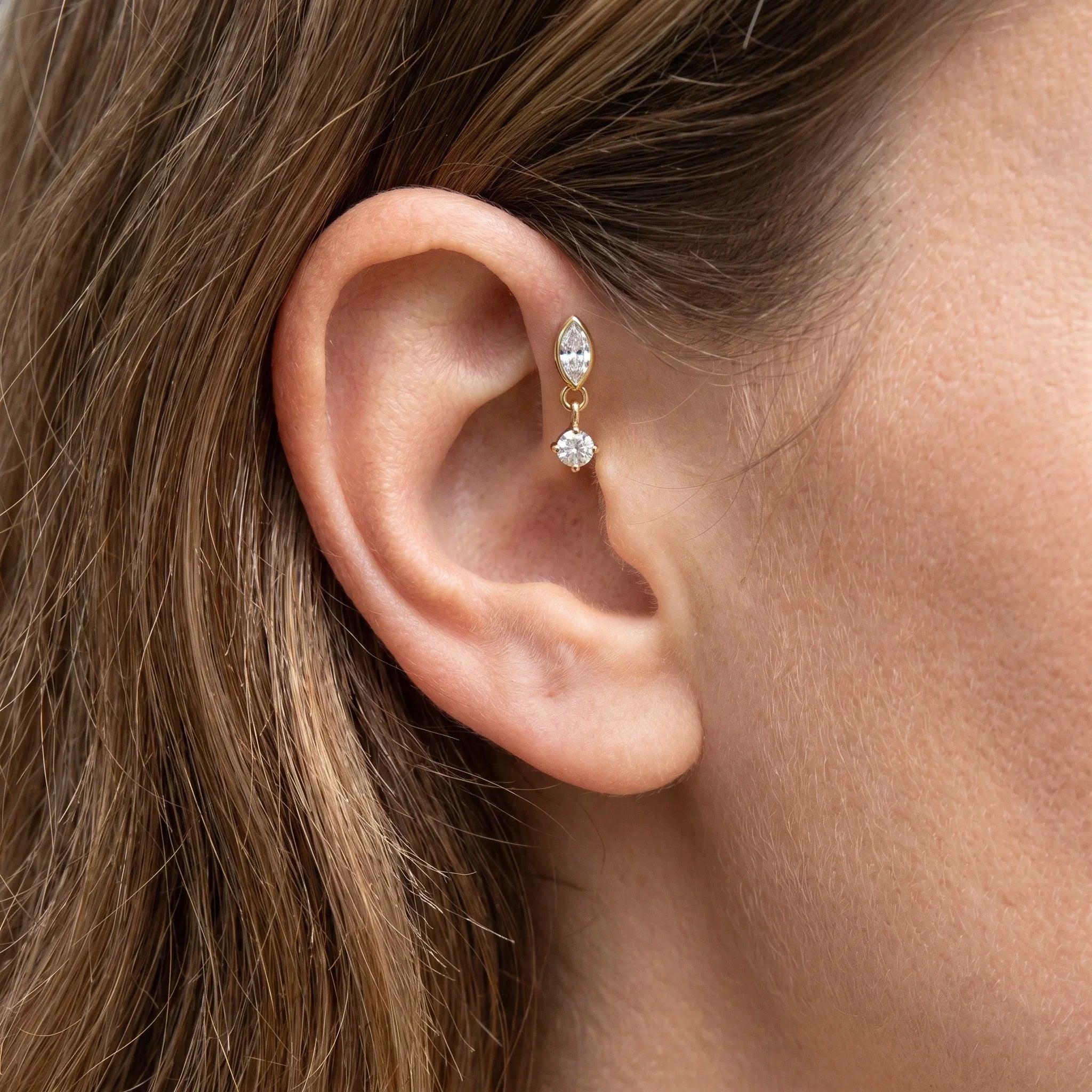 Close-up profile view of a model wearing a silver marquise drop stud