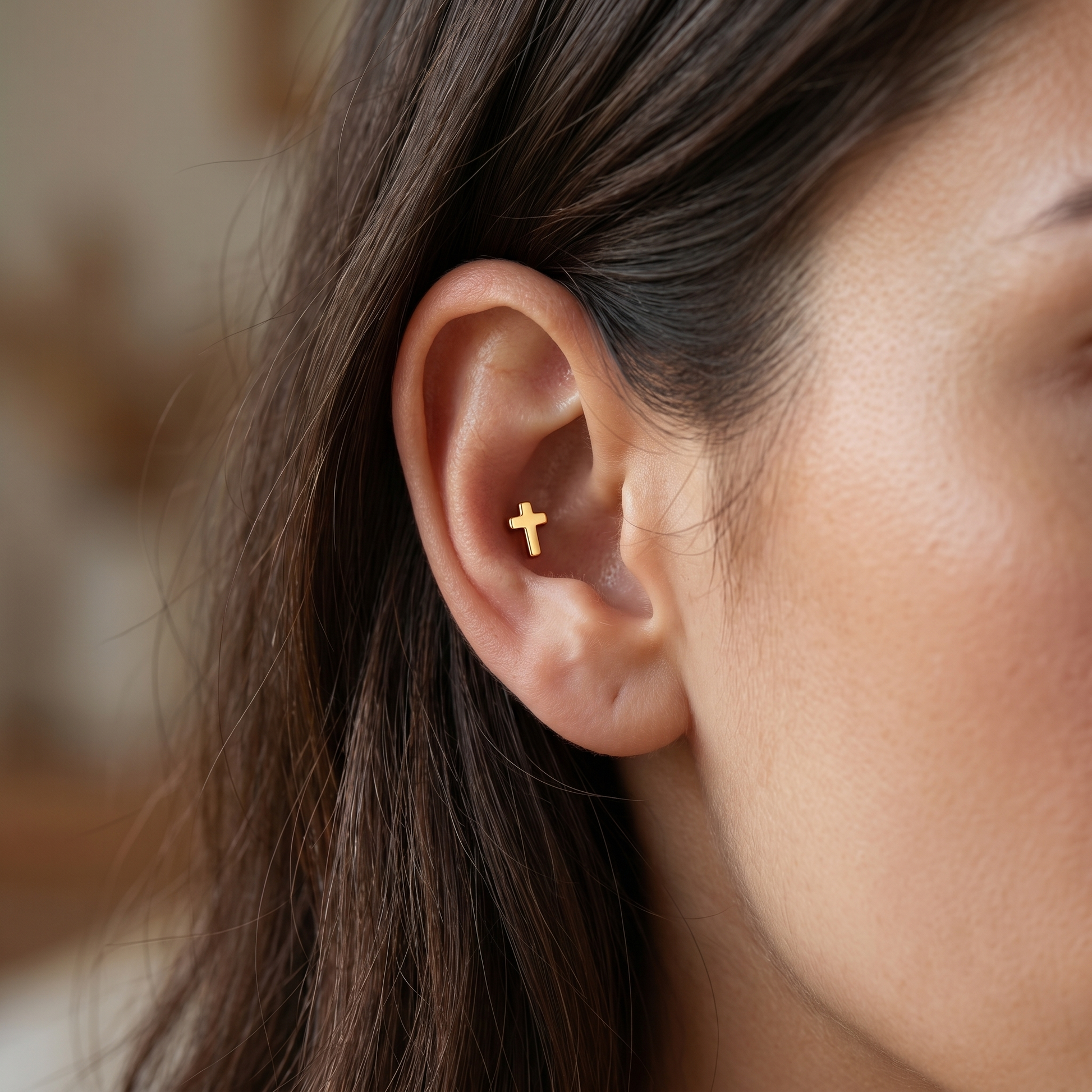 Gold minimal cross stud worn cleanly in a conch ear piercing placement.