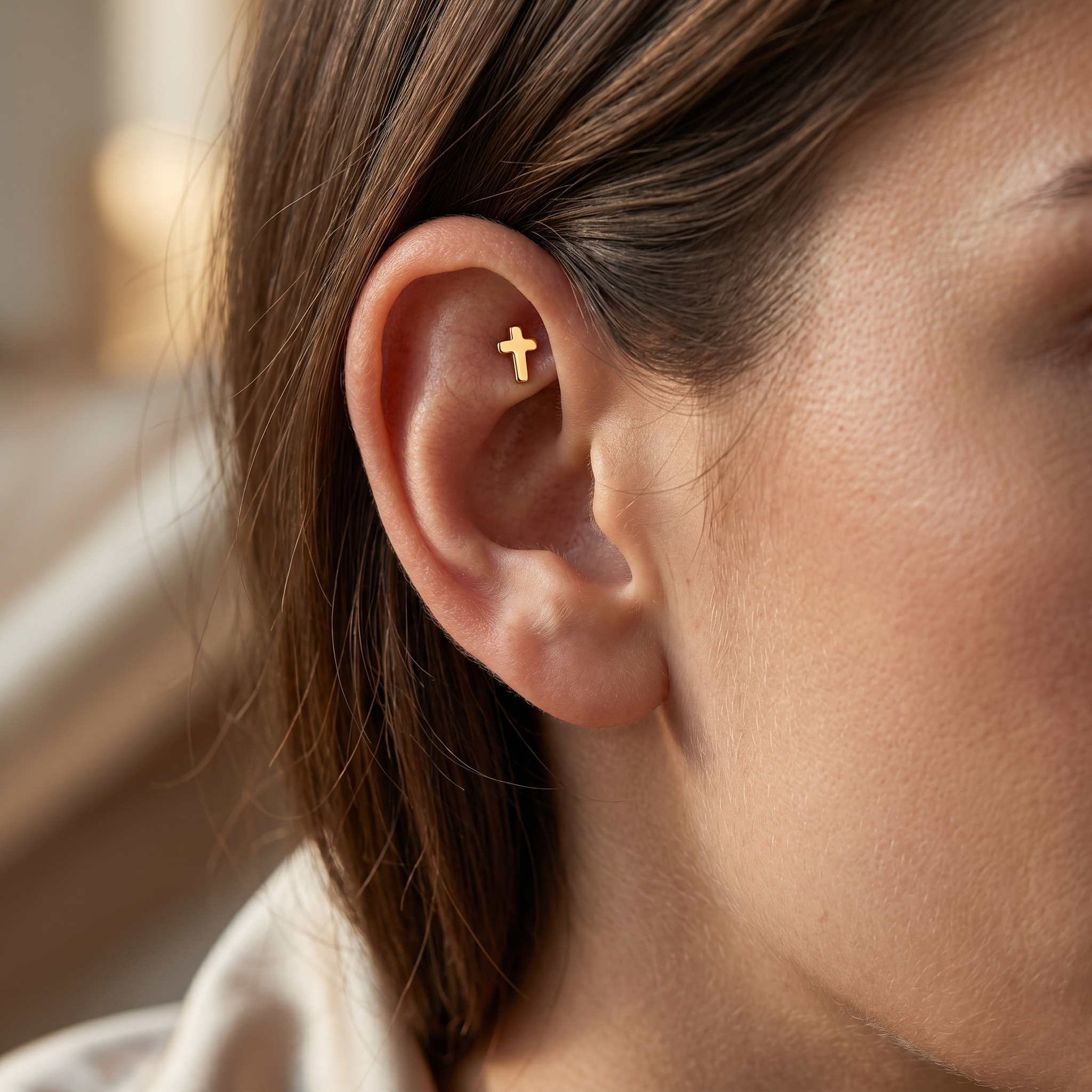 Gold minimalist cross earring worn securely in a faux cartilage placement.