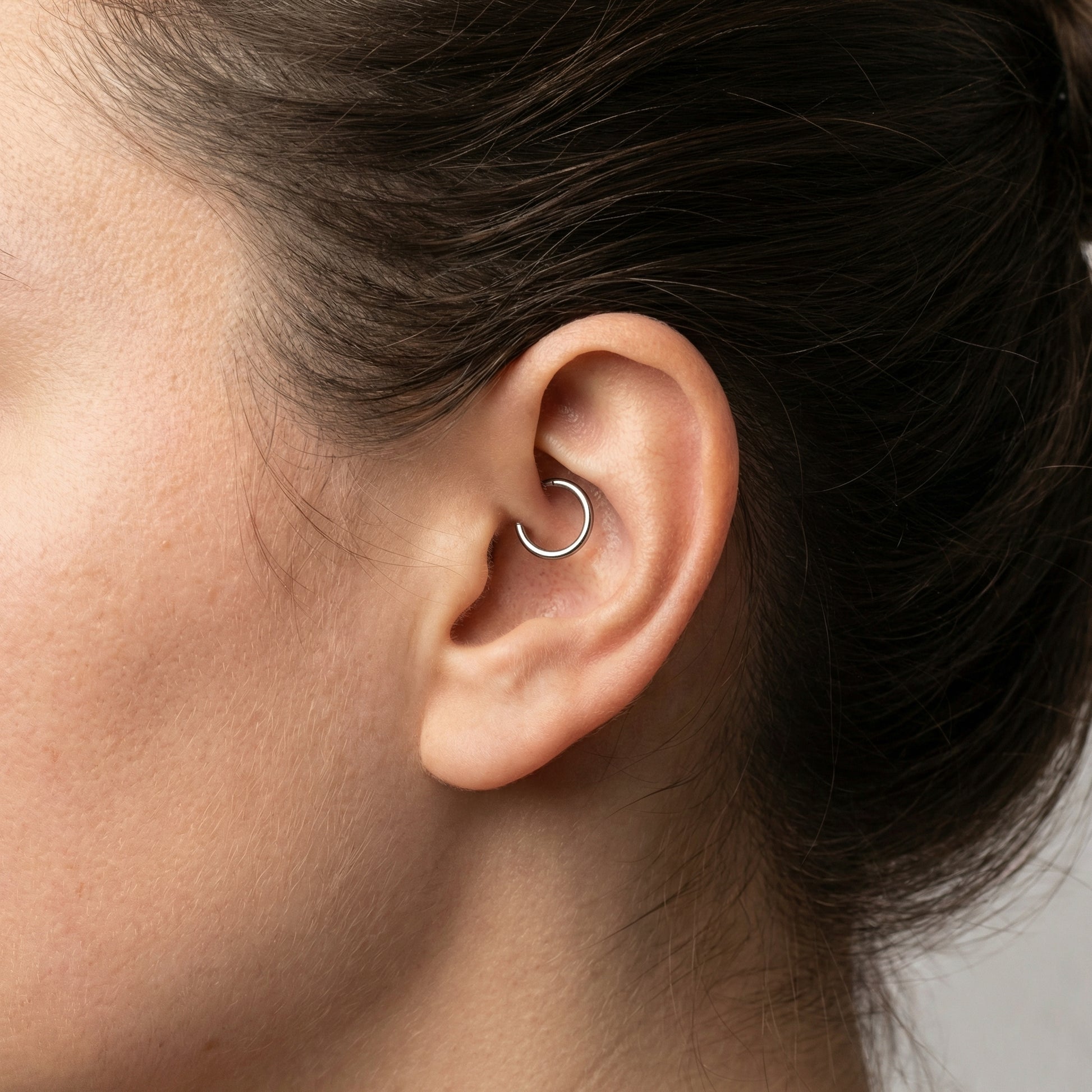 Close-up of a gold titanium plain clicker hoop ring styled inside a