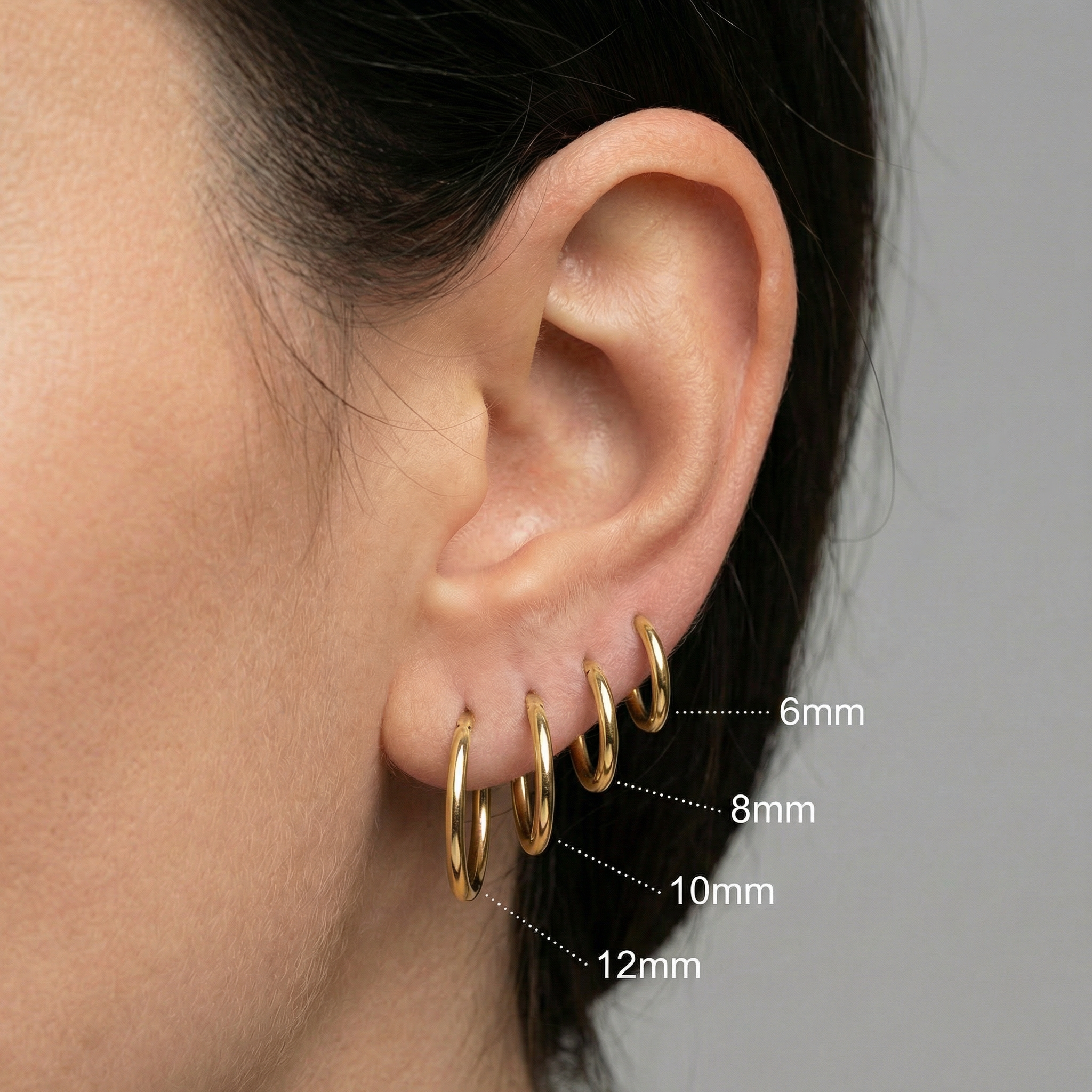 Stacked ear curation displaying four gold titanium clicker hoops ordered from 6mm