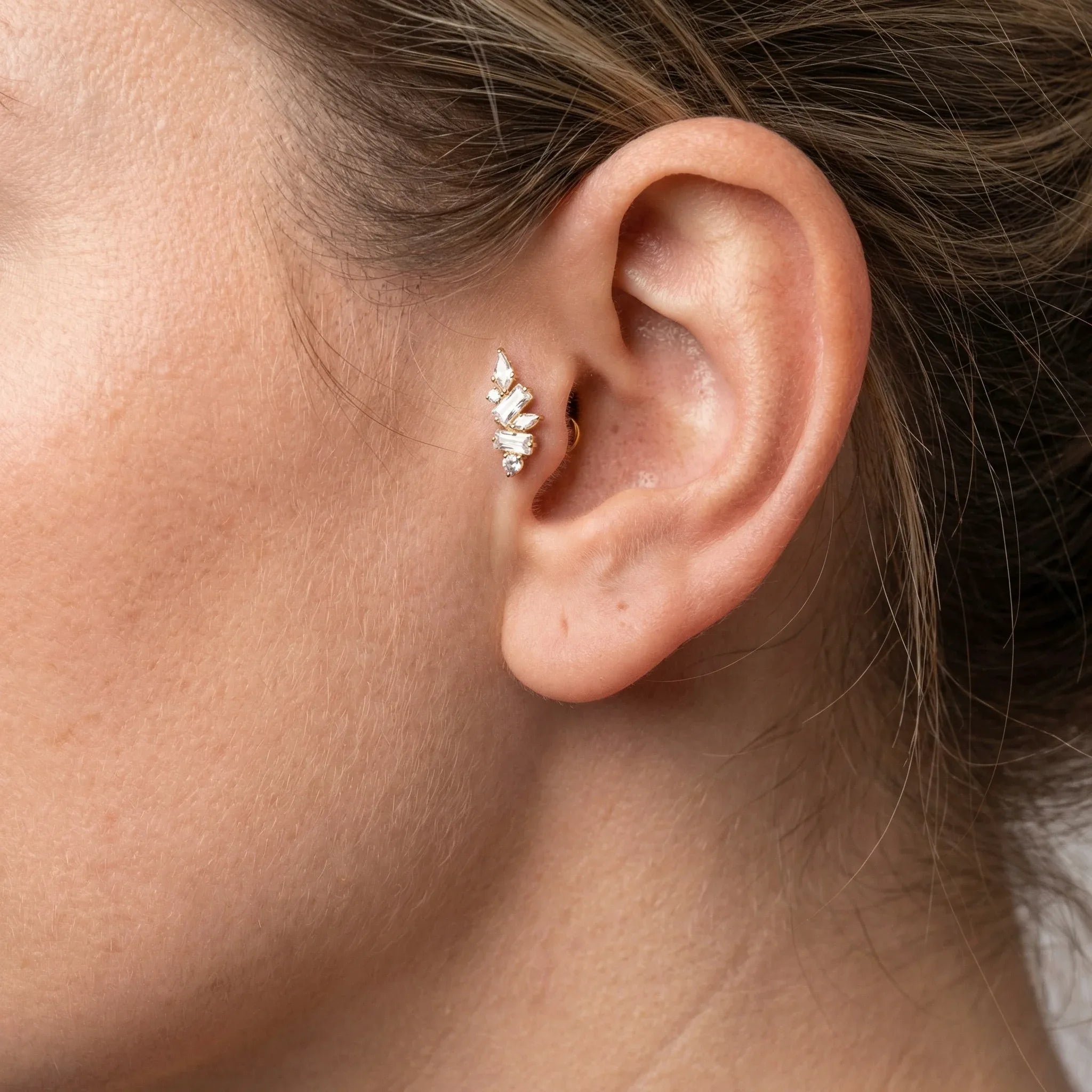Close-up of a silver zircon cluster worn in a model's cartilage piercing.