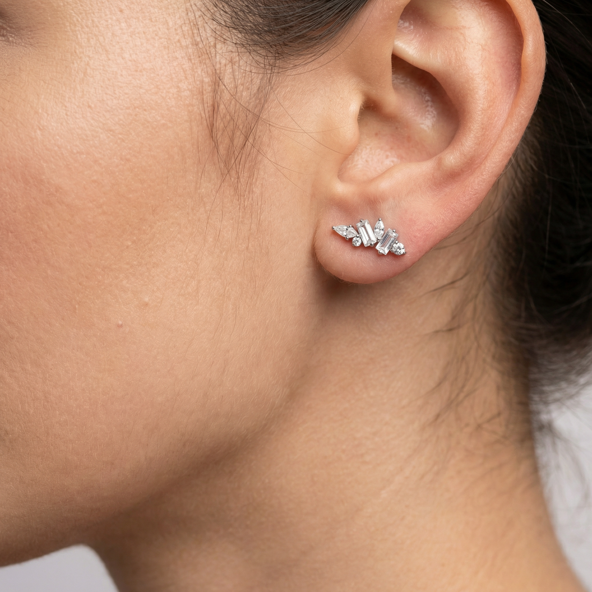 Profile view of a model wearing a silver multi-stone zircon cluster in