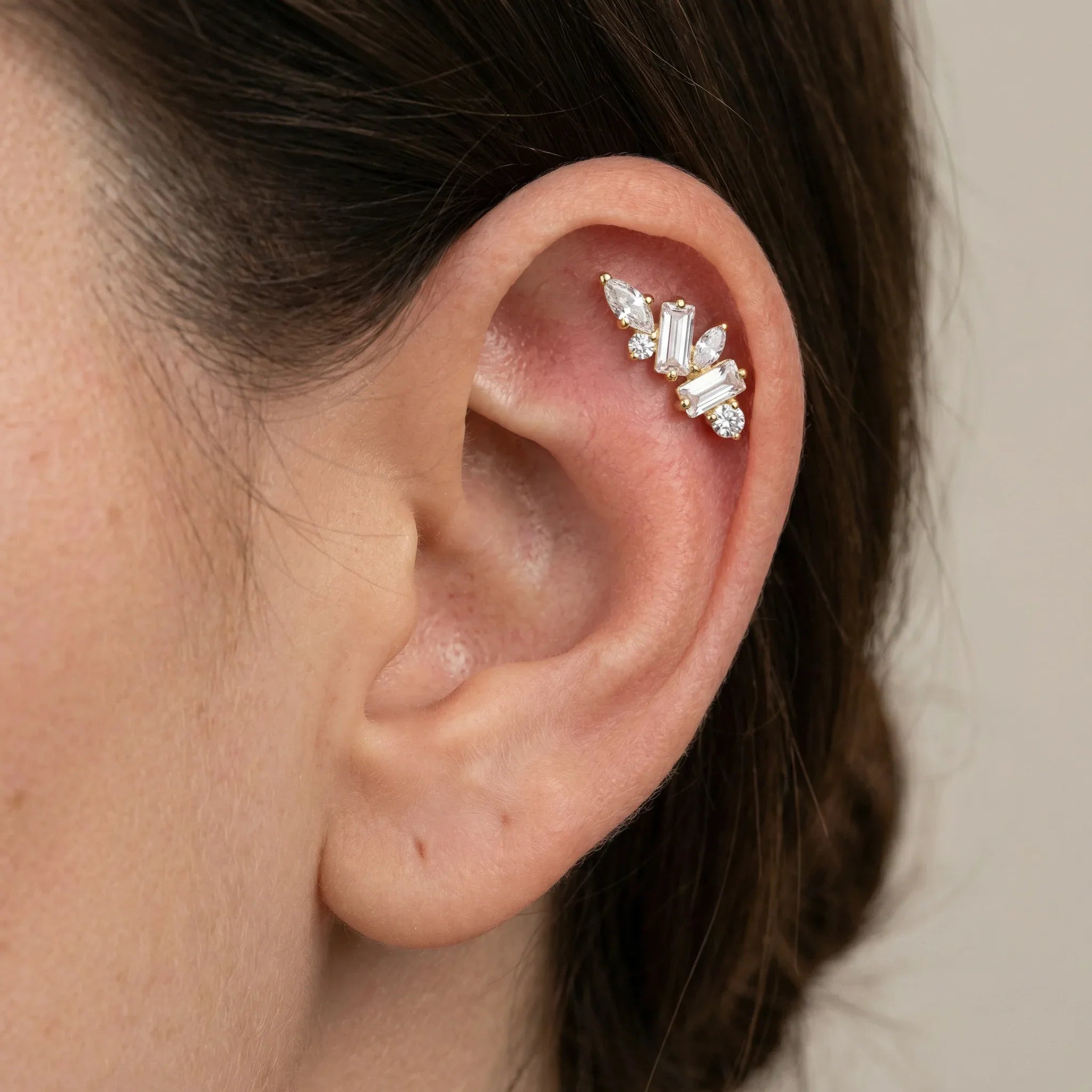 Gold multi-stone zircon cluster styled beautifully on a model's ear piercing.