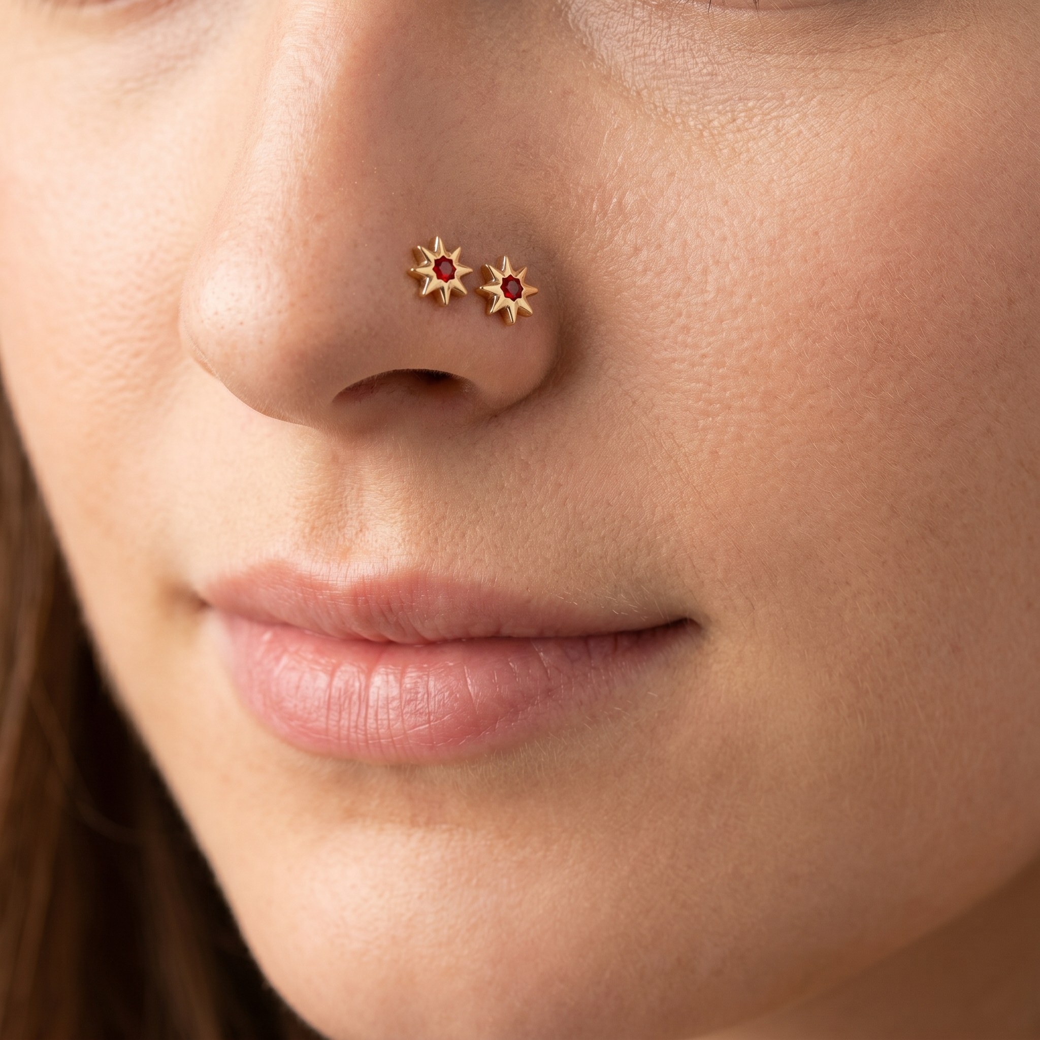 Two north star nose studs styled as a double nose piercing on one nostril