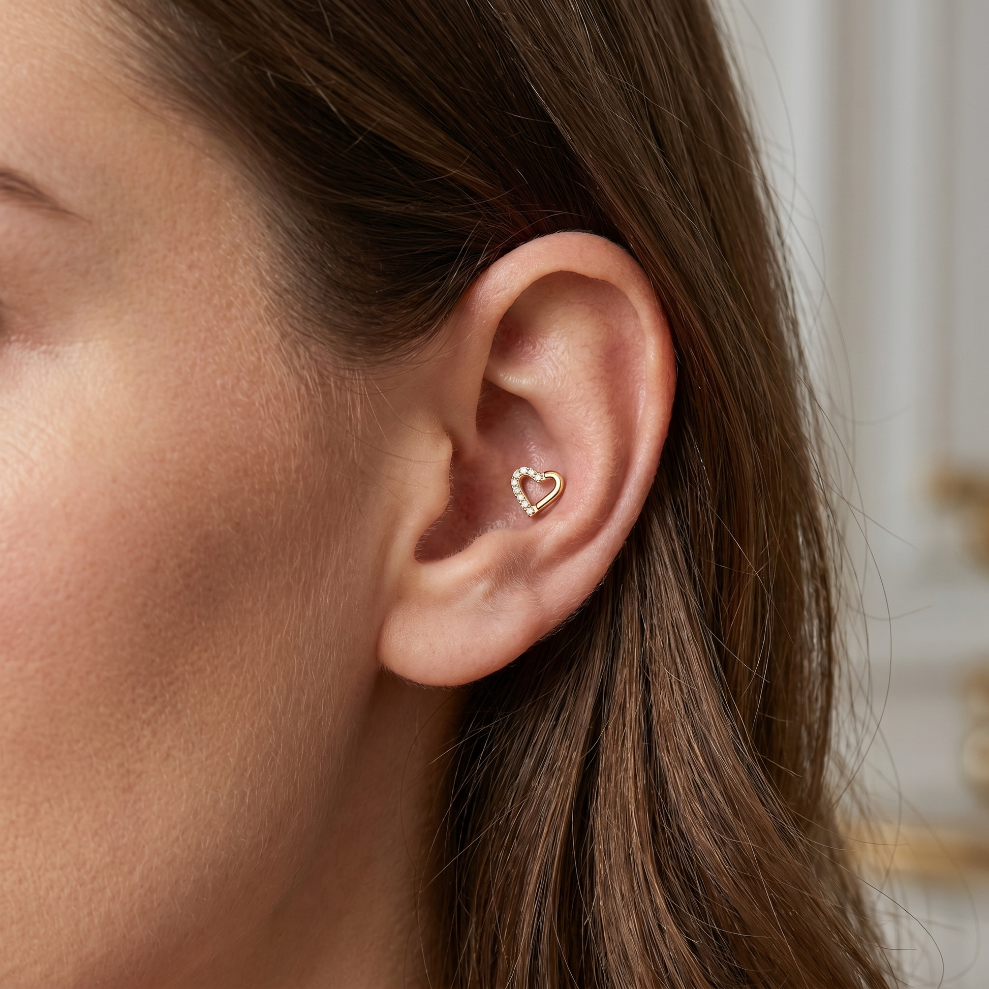 Gold open heart cartilage earring worn securely in a deep ear